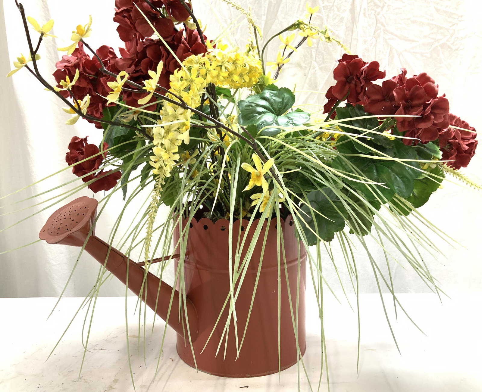 Indoor Garden Faux Flowers in Tole Water Can: forsythia and geranium Faux Flowers in Toleware water can, Floral colors yellow, red, and green with brick red painted water can. Measures 26. In tall, 28.5 in x 23 in. wide. Remove flowers and use wa