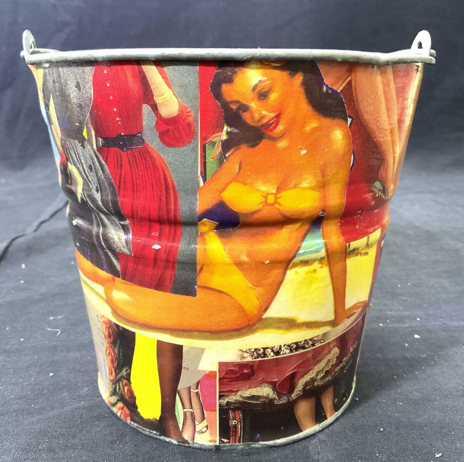 Female Figure Collage Metal Ice Bucket: Ice bucket is metal. Piece has collage of various female figures, pin up girls, models etc. Piece has arched handle. Measures approx 8.75 inches tall 7 inches wide. Ice bucket, metal ice bucket, colla