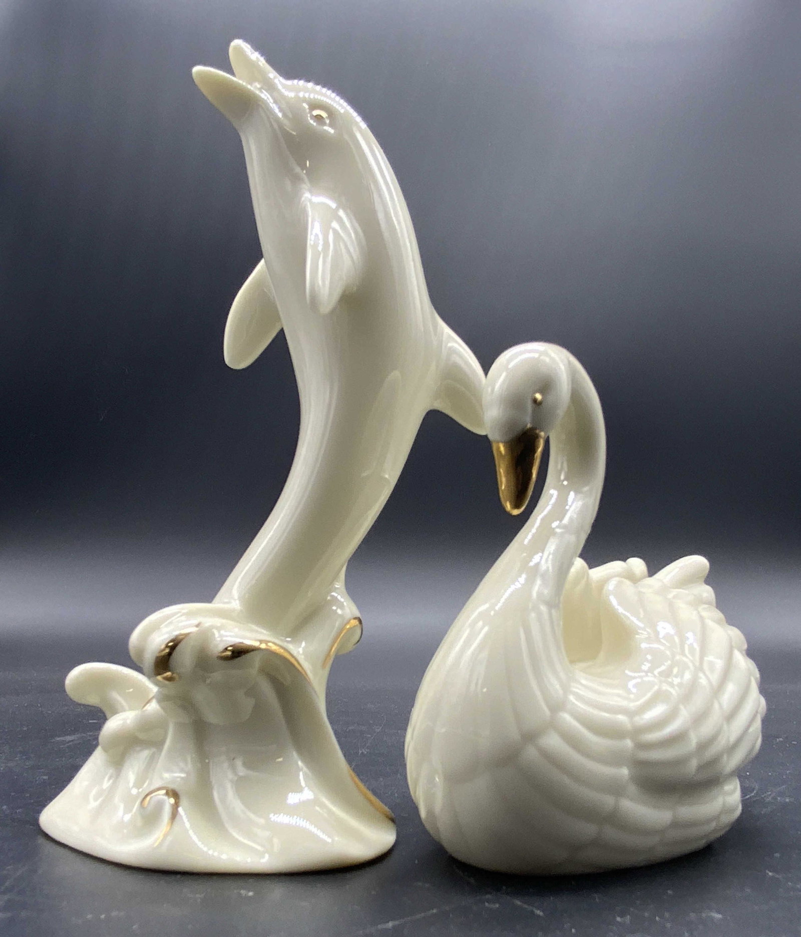 LENOX Handcraft Porcelain Swan & Dolphin Figurals: Lot 2 handcrafted porcelain swan and dolphin Figurals. Gilt accents to each piece. Undersides signed LENOX. Stockers read HANDCRAFTED IN INDIA. Largest piece, dolphin, measures approx 4H x 2W in. Some