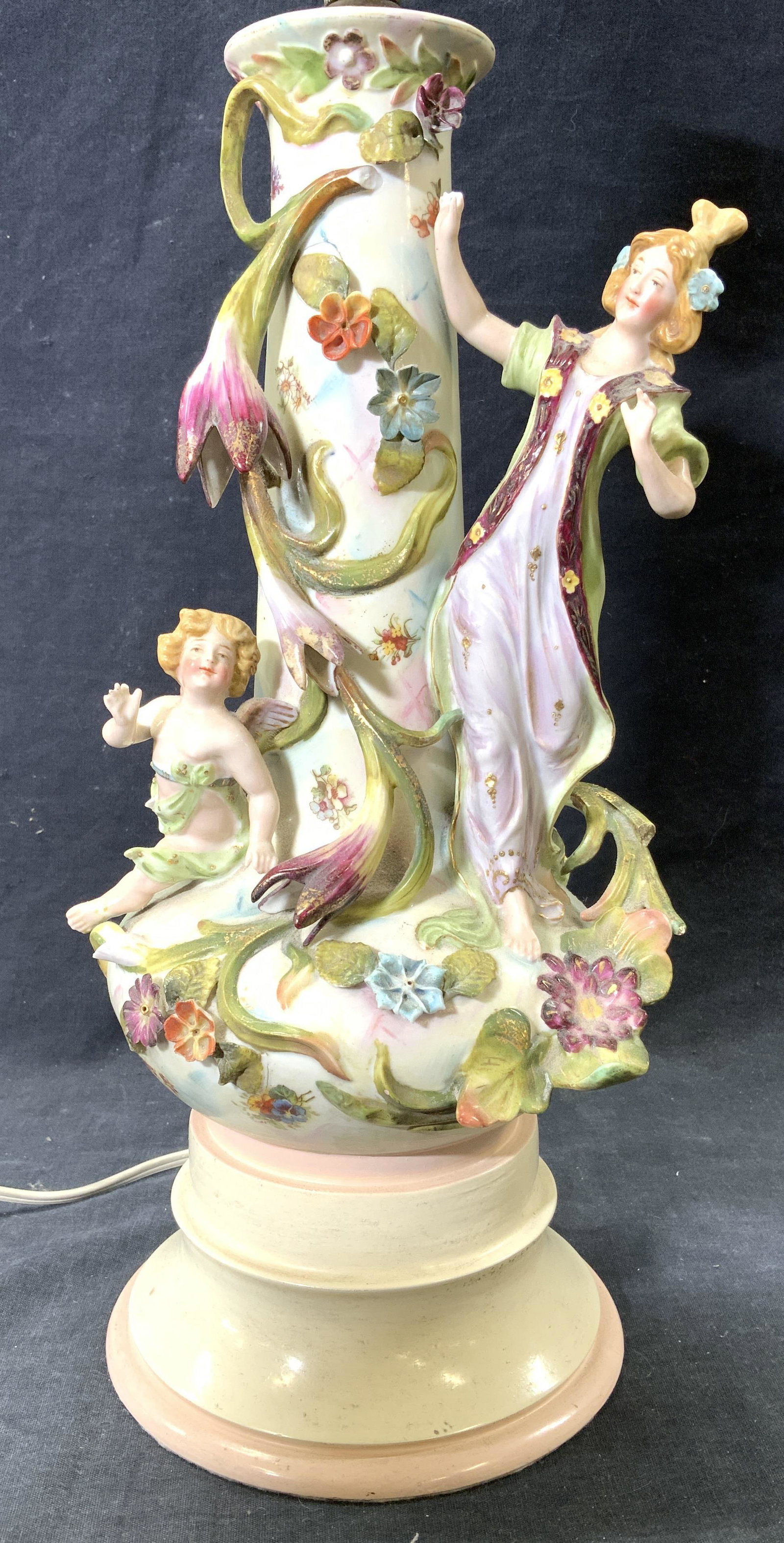Vntg Porcelain Lamp W Floral & Figural Detail: Lamp is vintage. Piece is porcelain with cherub & female figure detail. Lamp includes harp & porcelain finial. Piece measures approx 27 inches tall 6 inches wide. Lamp, porcelain lamp, Porcelainware, 