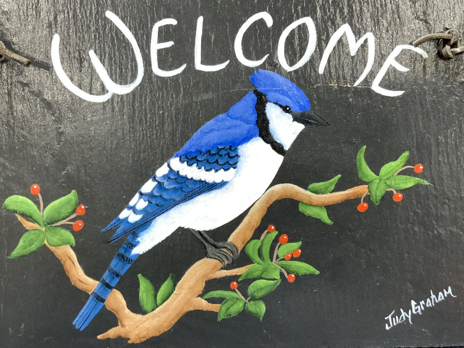 JUDY GRAHAM Signed Blue Jay Painted Slate Sign: Signed on lower right Judy Graham. Acrylic painting of a blue jar perched on a tree branch with Welcome above. Backside is marked Slate From Old roof, bldg 622, USMA, West Point NY. approximately 8 x 