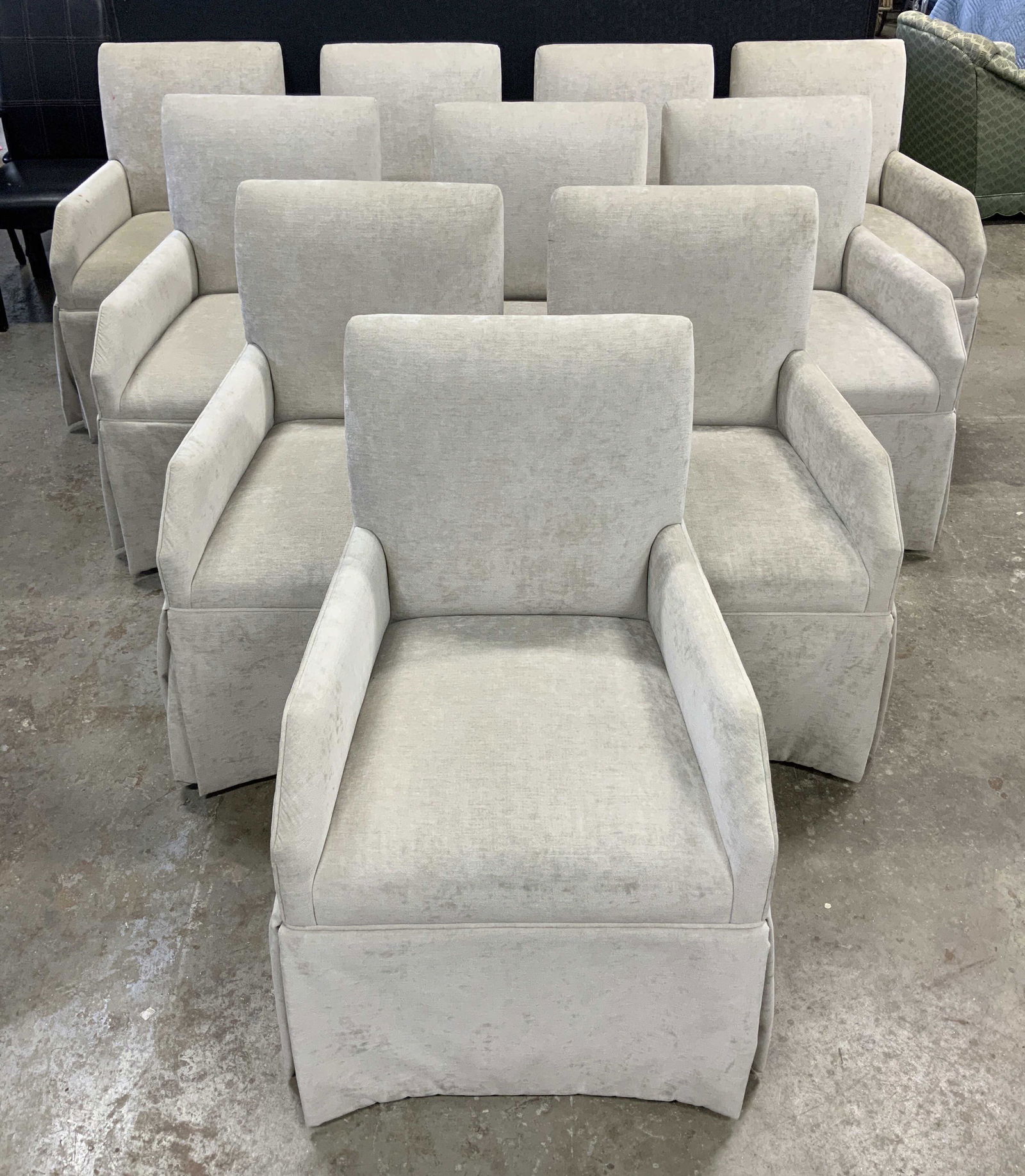 Set 10 THE CHARLES STEWART COMPANY Skirted Chairs: Undersides have tags which read THE CHARLES STEWART COMPANY. Each chair has a light slate tan tone. Chairs are each skirted & have armrests. Each chair measures approx 36 in height by 24 in wide by 27