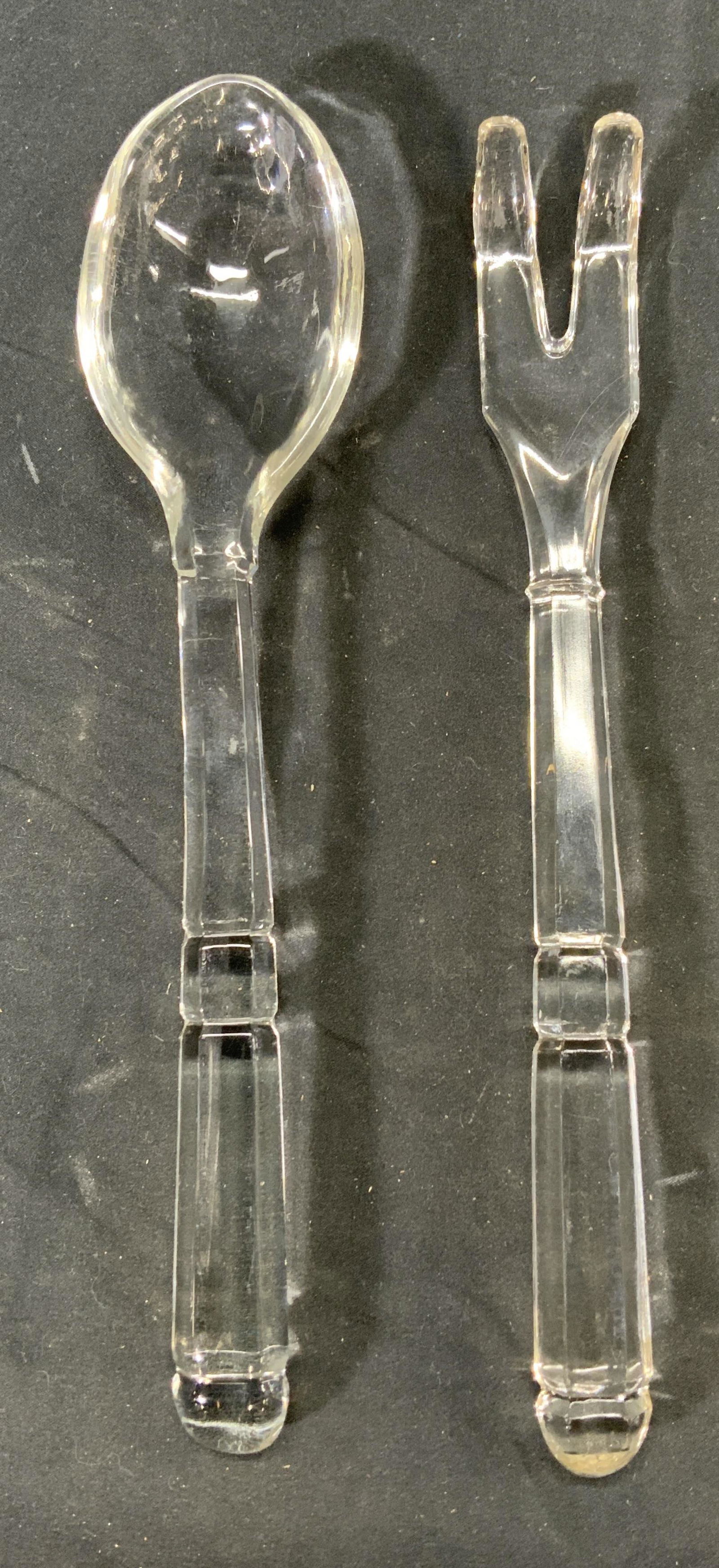 Set 2 Vintage Glass Serving Fork & Spoon: Set of 2 vintage glass serving utensils. 1 fork, measures approx. 10 inches long. 1 spoon, measures 10.25 inches. Surface wear to both pieces consistent with use and exposure. Glass serving spoon, gla