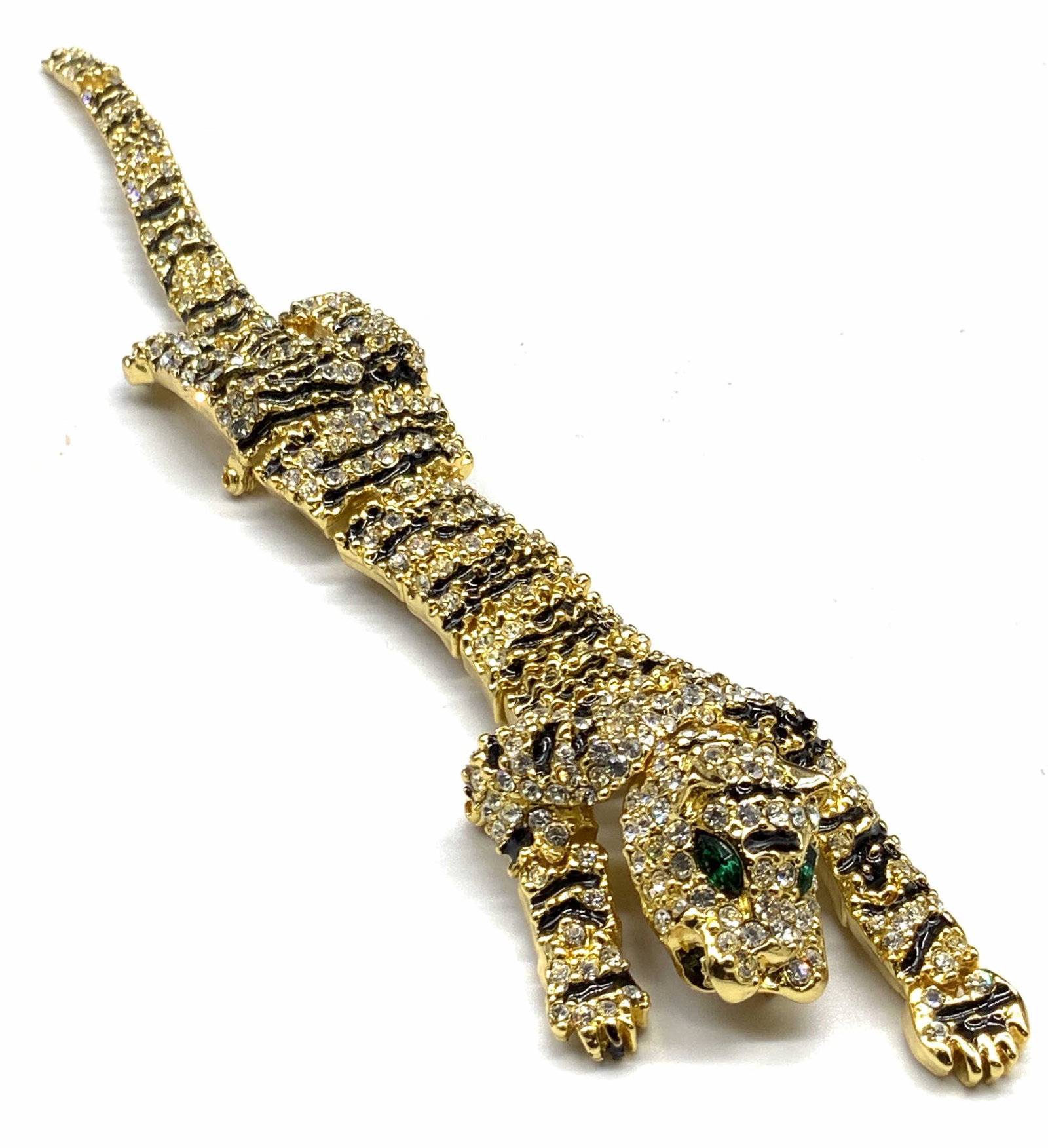 Vintage Oversized Articulated Crystal Tiger Brooch: A vintage oversized articulated tiger / panther brooch. Gold tone metal. The piece is bejeweled with faceted colorless & emerald green crystals alongside black enamelwork. The body is in panels and mo
