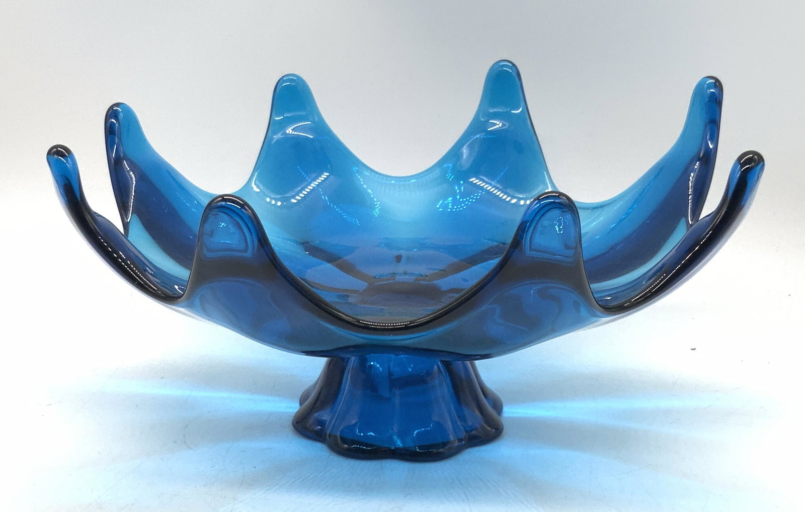 Vntg Blue Art Glass Lotus Rim Pedestal Candy Dish: A vintage blue art glass lotus rim / tulip rim / ruffled rim pedestal candy dish. Thick walled and weighty glass. Measures approx 4.75H x 10W in. Some surface wear consistent with age and use. Vintage
