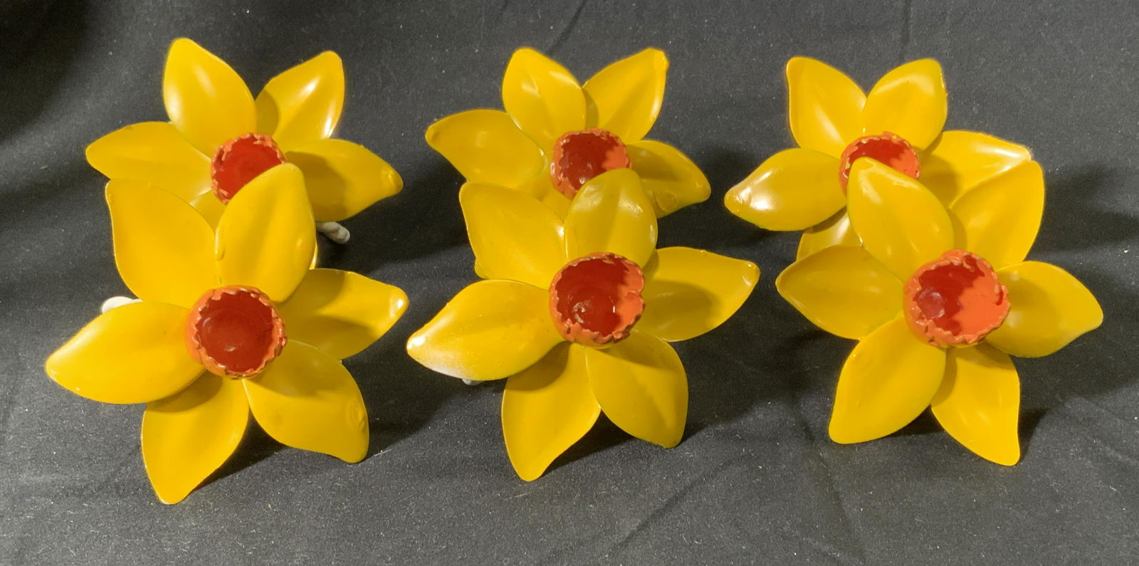 Set 6 Enameled Metal Daffodil Napkin Rings: Set of 6 enameled metal daffodil napkin rings in hues of yellow and orange. Some surface wear consistent with exposure. Made in Italy. Measure approx. 3.5 inches diameter (flower) and 1.75 inches diam