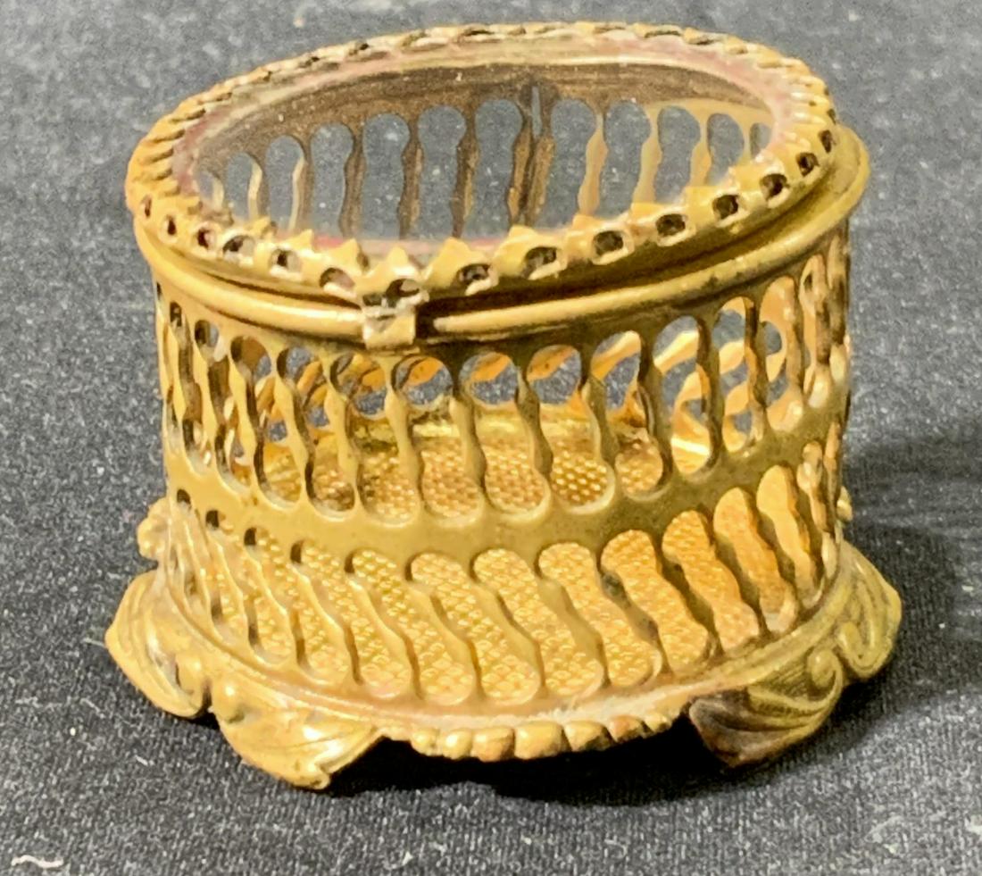 Vintage Brass Pill Box: Vintage brass pill box with open punched metal body and glass cover. Surface wear consistent with exposure. Measures approx. 1 3/8 inches diameter and 1 inch tall. Pill box, brass pill box, decorative