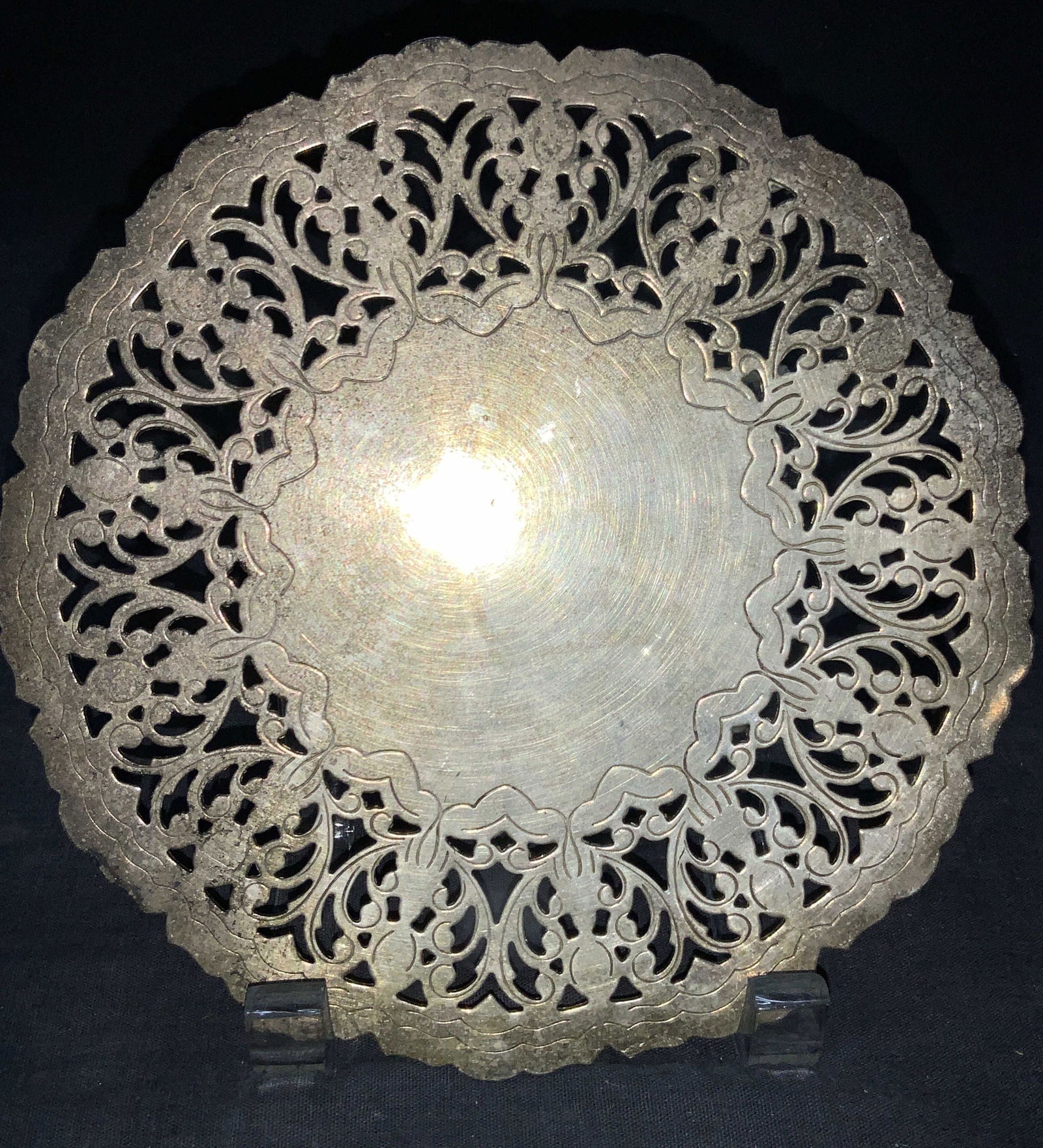 Vintage Silver Plate Trivet, Denmark: Vintage silver plate trivet with scroll cut out patterns on edges. Marked on underside Silver Plate, Denmark. Approximately 7 inch diameter. Evident surface wear. Vintage silver plate trivet, vintage