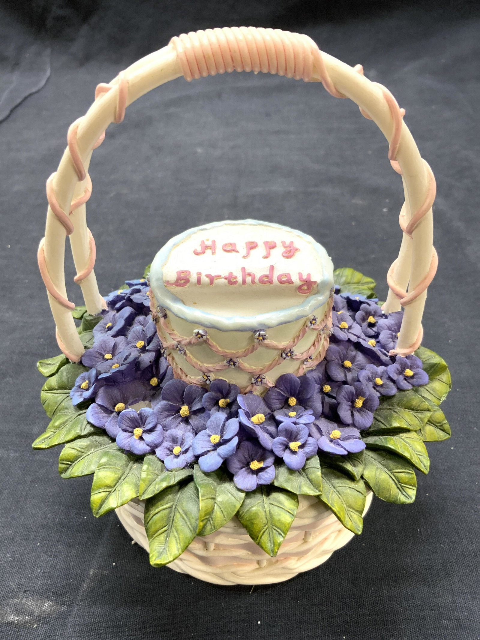 ARTISAN FLAIR INC Porcelain Happy Birthday Basket: Underside reads. ARTISAN FLAIR INC “A BASKET FOR YOU” GREETING BASKETS TOO. Piece is porcelain. Underside reads HAND PAINTED. Basket has floral & leaf detail & cake which reads HAPPY BIRTHDAY. Mea