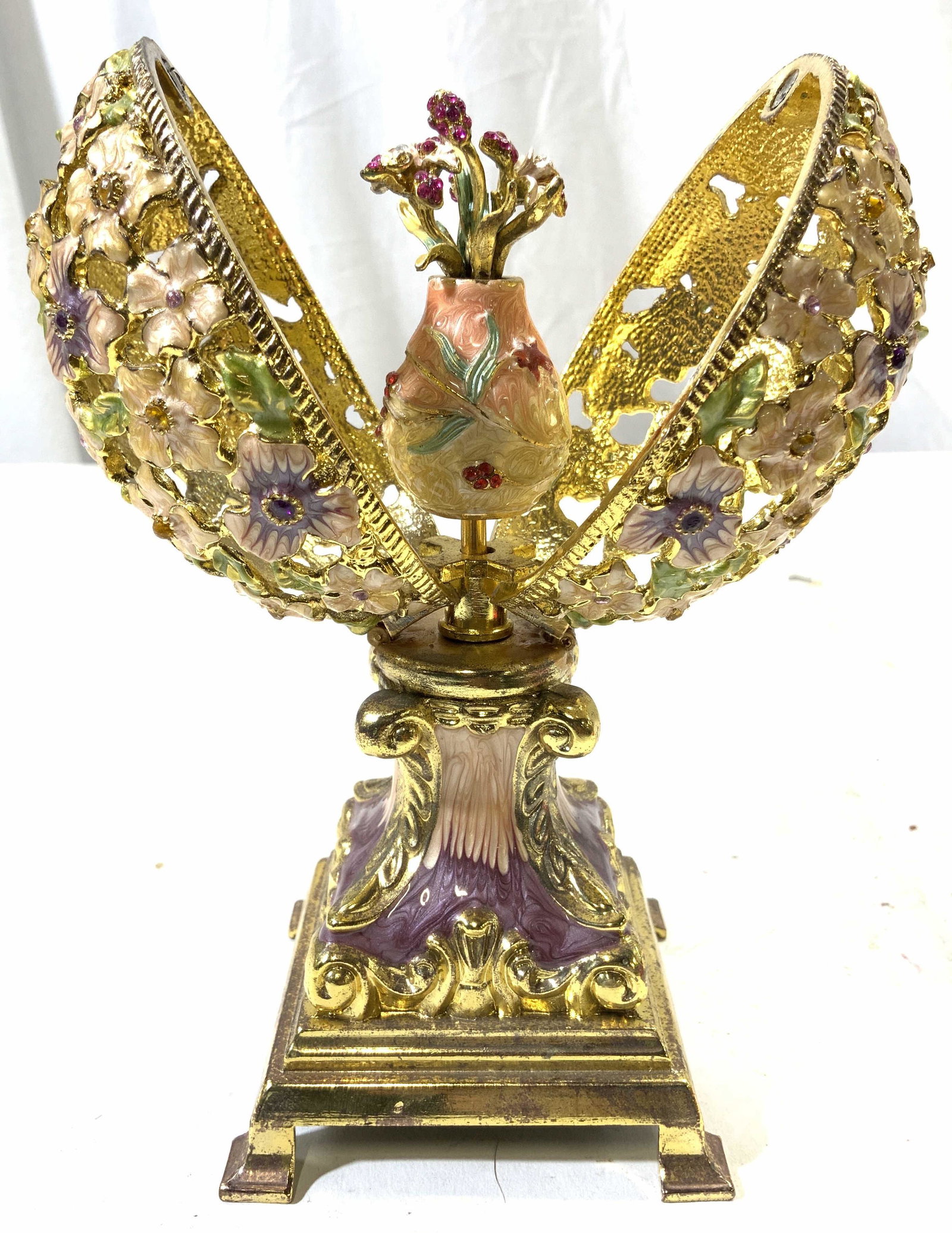 Enamel & Brass Egg Shaped Music Box: Music box is egg shaped. Piece is enameled with multi toned floral & leaf detail. Piece has gold toned metal base which appears to be brass. Piece opens to reveal flowers in vase figure. Box measures