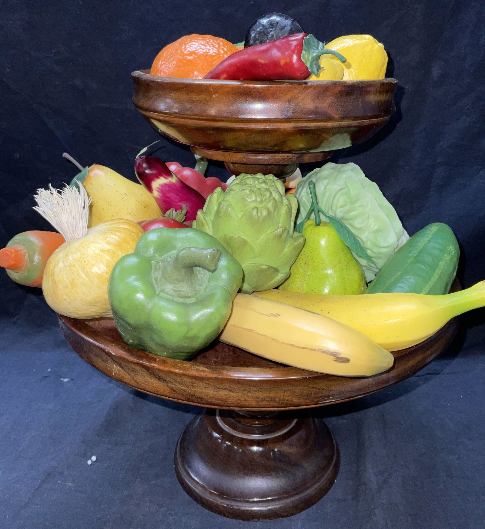 Two Tiered Wooden Holder W Faux Veg & Fruits: Two Tiered Wooden Holder W Faux Veg & Fruits. 26 pieces of faux food surface wear to pieces are consistent with use and age. Faux fruits & veggies are soft plastic material, one orange 2 lemons are ma