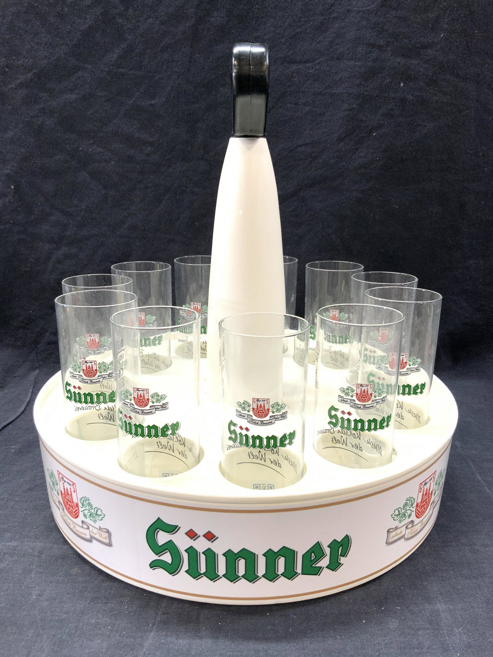 SÜNNER KOLSCH Beer Glass Holder Glasses & Coasters: Lot includes 11 glass within circular shaped holder. Lot also includes 15 coasters. From Sunner Beer Hall Cologne Germany. Holder measures approximately 12.5 inches tall 12.5 and wide. Sunner beer, Su