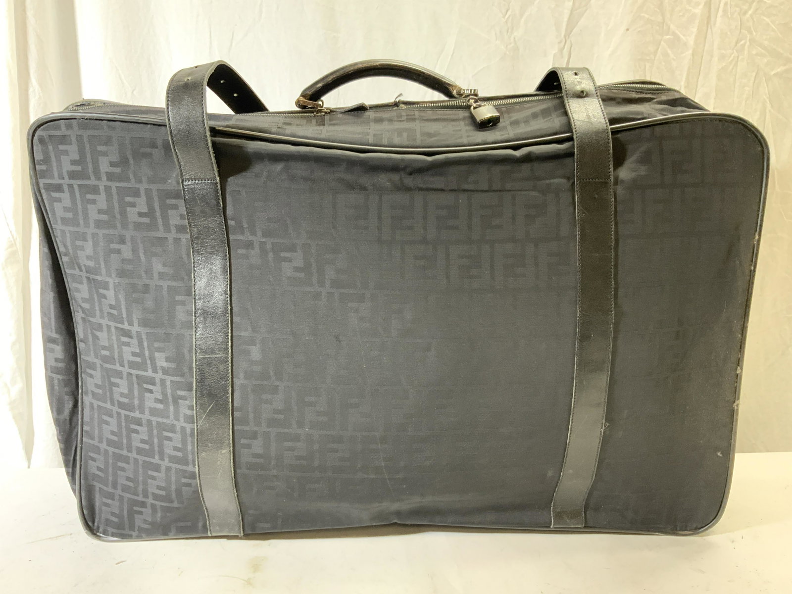 Vintage FENDI NYLON Suitcase In Black: Suitcase has FENDI Inscription in multiple areas. Suitcase is black toned & appears to be nylon & leather style. Piece has zipper & belt style fasteners. Piece measures approx 28 inches long 20 inches