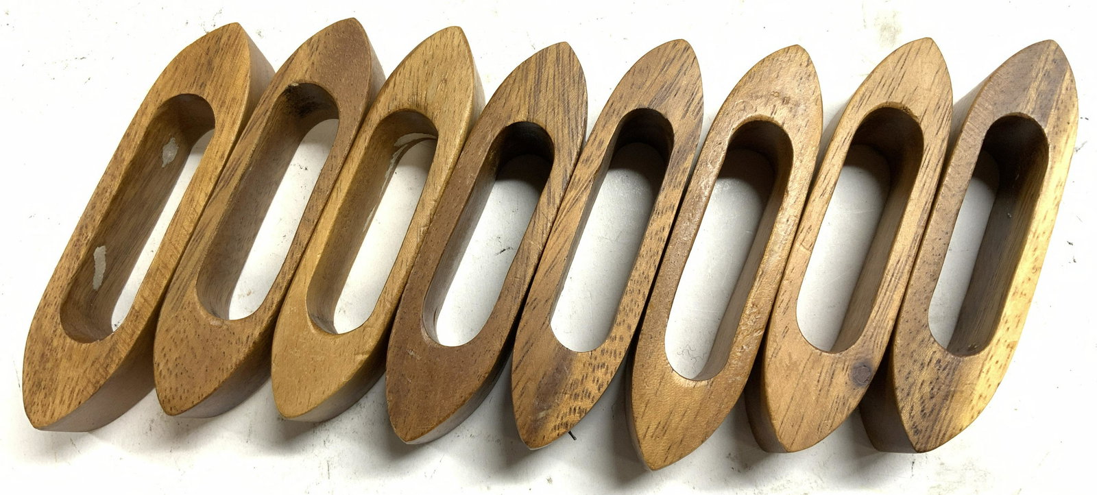 Set 8 Wooden Napkin Rings: Lot includes 8 napkin rings. Each appear to be wooden, possibly teak, possibly oak, possibly veneer. Each piece measures approx 3.75 inches long 1 inch wide. Napkin rings, wooden napkin ring, napkin h