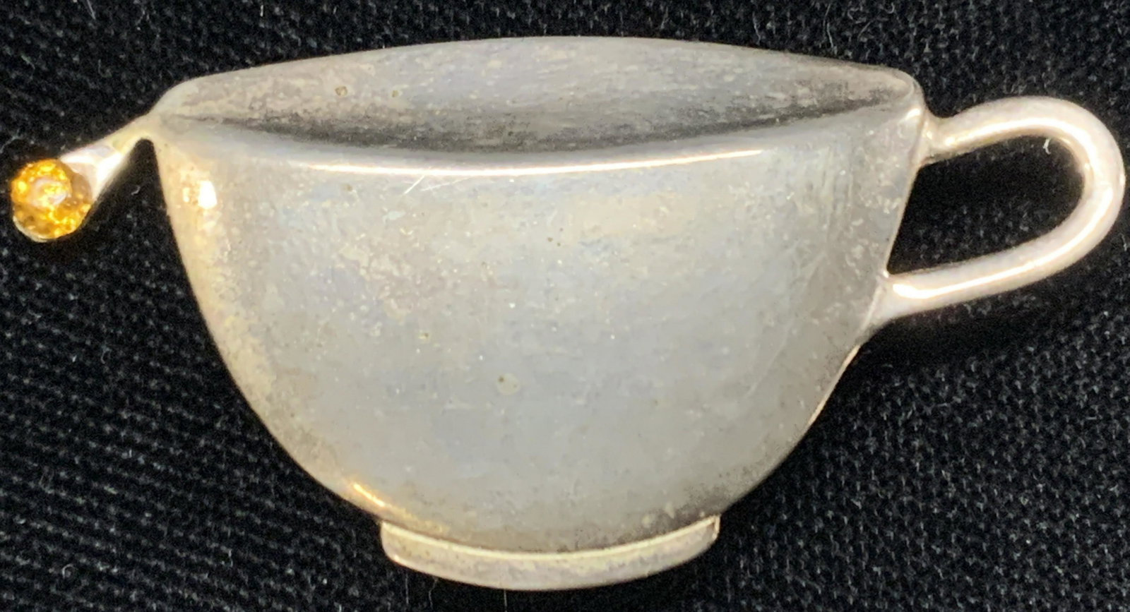 Vintage Tea Cup Pin: Vintage pin made to resemble a tea cup with a drop coming off corner with a faceted amber toned rhinestone. Approximately 0.75 inches long and 1.5 inches wide. Vintage brooch, brooch, vintage jewelry,