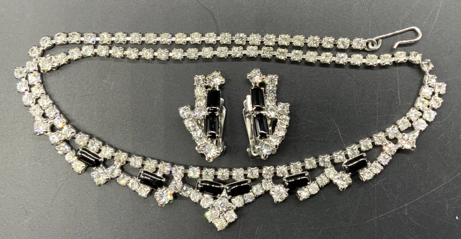 Set Bejeweled Crystal Earrings & Choker Necklace: Set of Bejeweled crystal clip on earrings and choker necklace. Earrings have prong set faceted colorless crystals and black cabochons, measure approx. 1 x .5 inches. Necklace has prong set faceted col