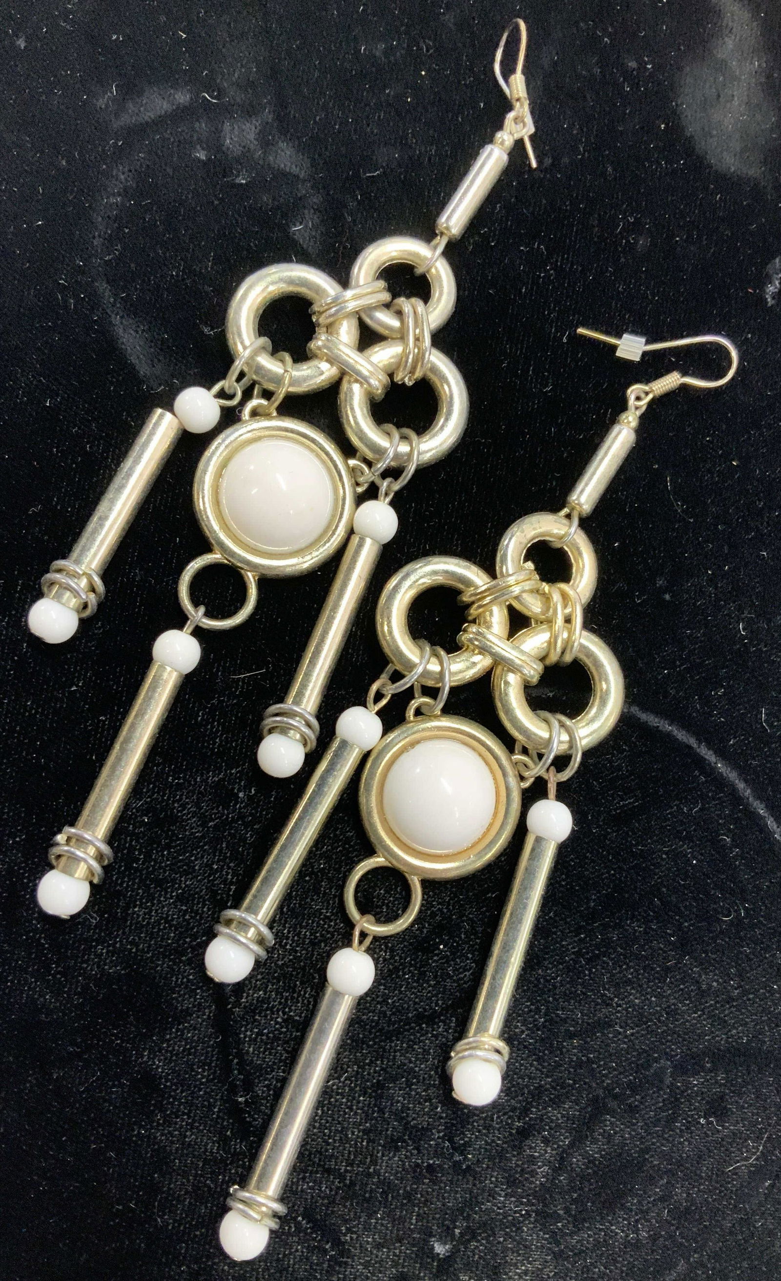 Modernist Silver Toned Statement Earrings: Oversized pendant earrings in silver tone featuring white cabochon center and white beads. Fish back hooks, 5.5 in long, 1.5 in wide. Lightweight for its size. Property of Manhattan, NY estate Stateme