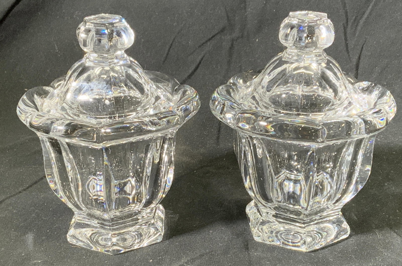 Pair BACCARAT Crystal Lidded Sugar Bowls: Pair of Baccarat crystal sugar bowls with lids. Both pieces trademarked to undersides and lids. In good condition, minor surface wear to each consistent with exposure. Measure approx. 3.5 inches diame