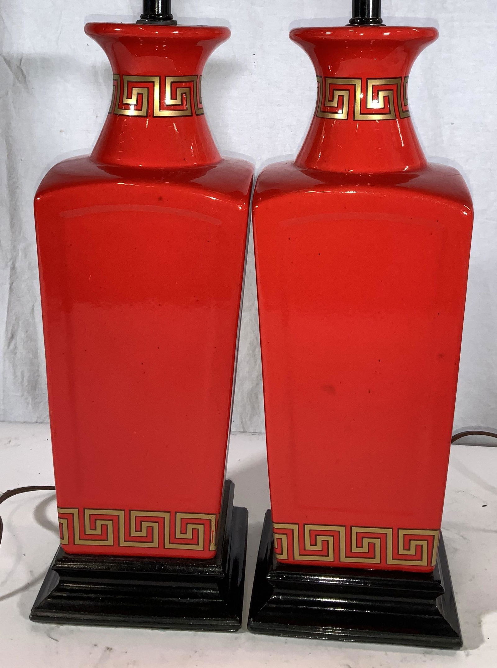Red Ceramic Greek Key Asian Lamp Pair: Bright red Asian square ceramic lamps with gilt Greek key pattern outlined in black. lacquered wood square Bases, turn switch , brass finials on top of brass light harps, add your touch of shade to th