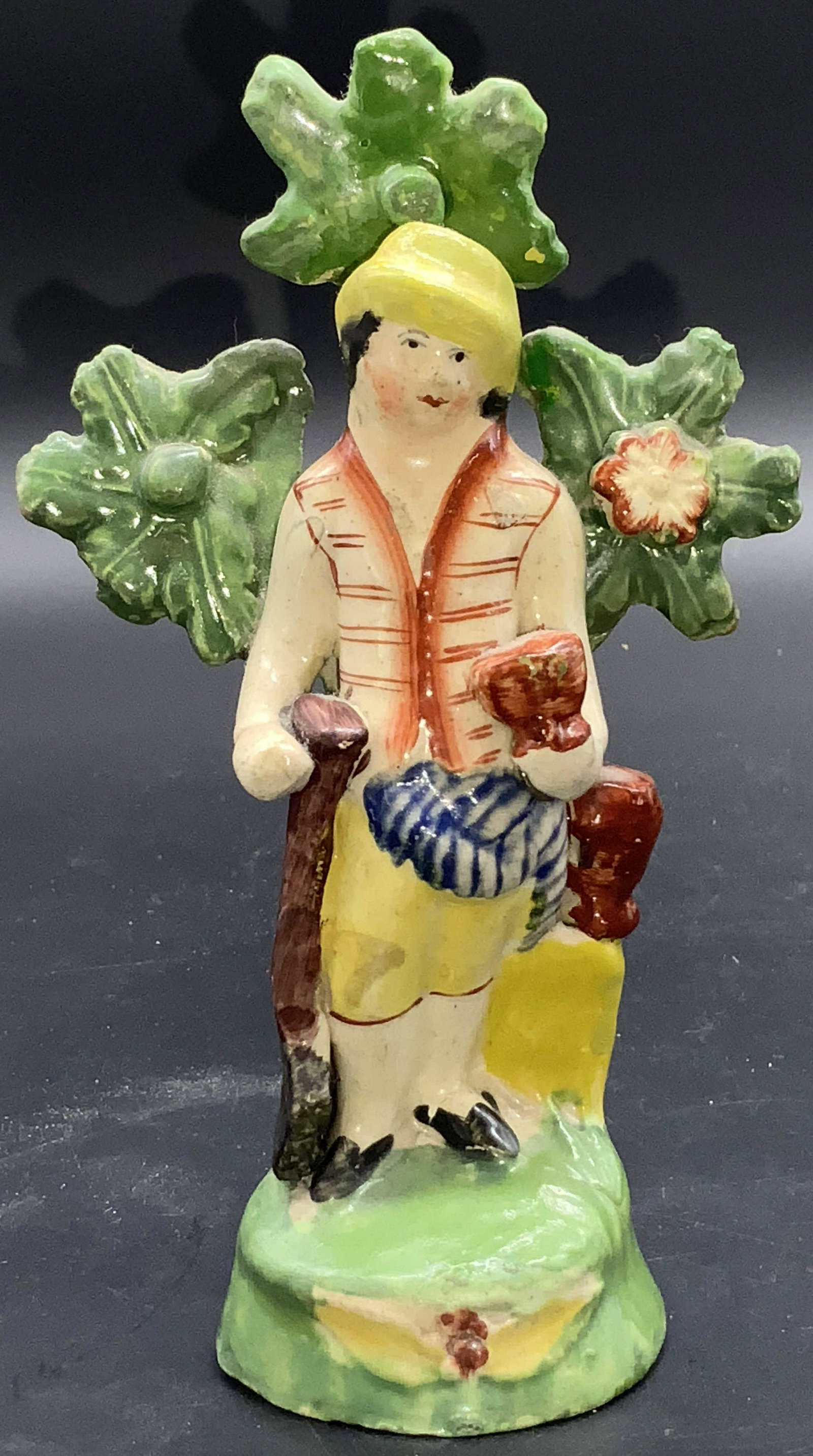 Antique Staffordshire Ceramic Outdoorsman Figural: A antique, possibly Staffordshire or Staffordshire style, ceramic figural depicting an outdoorsman amongst nature. The outdoorsman holds an axe in one hand and a cut in the other. Tree to his back, fl