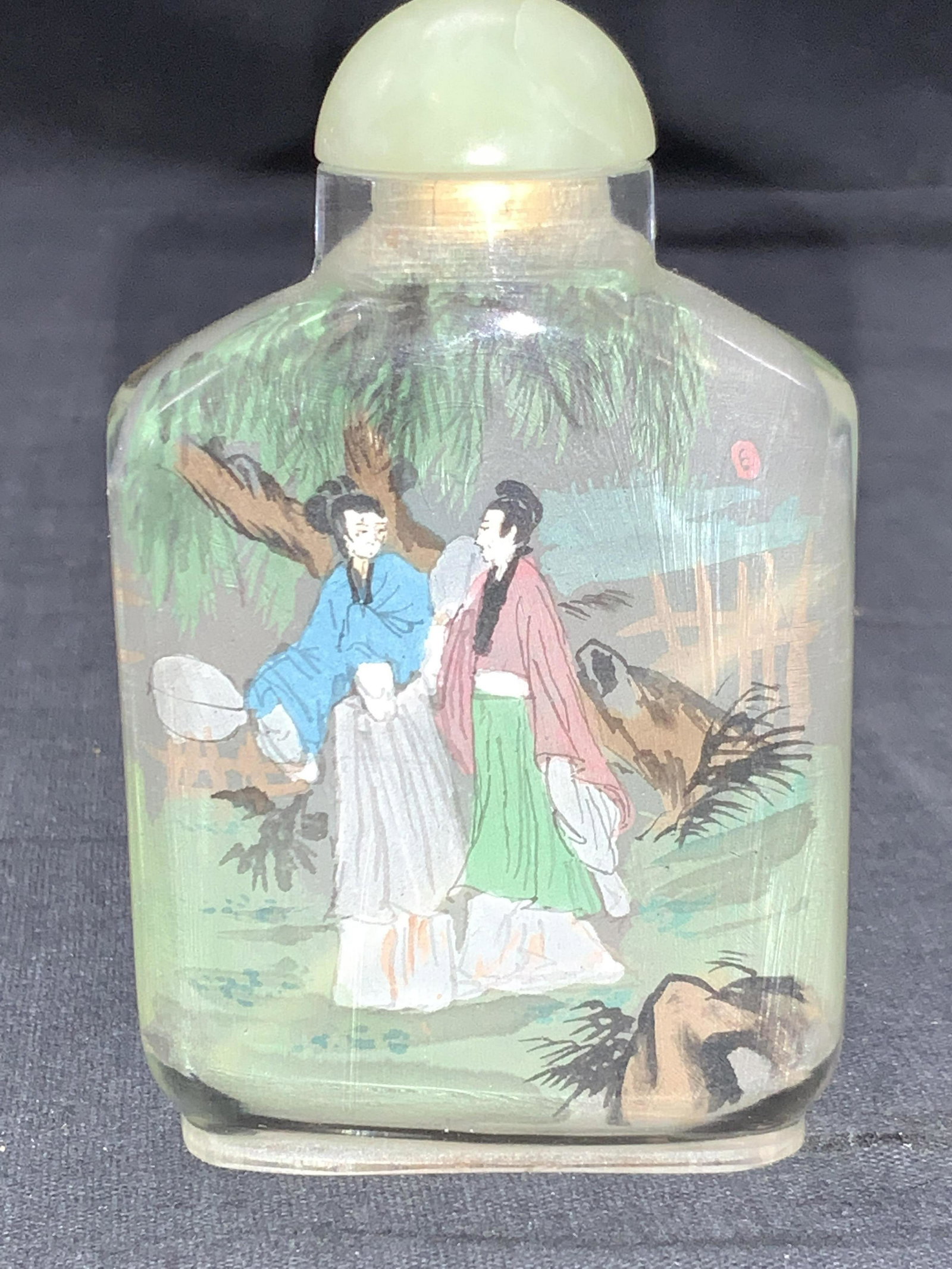 Vintage Hand Painted Asian Snuff Bottle: Vintage hand painted Asian glass snuff bottle. Glass bottle has interior painted scenes of people in traditional Chinese robes amongst a nature landscape. Stone stopper and carved bone spoon on inferi
