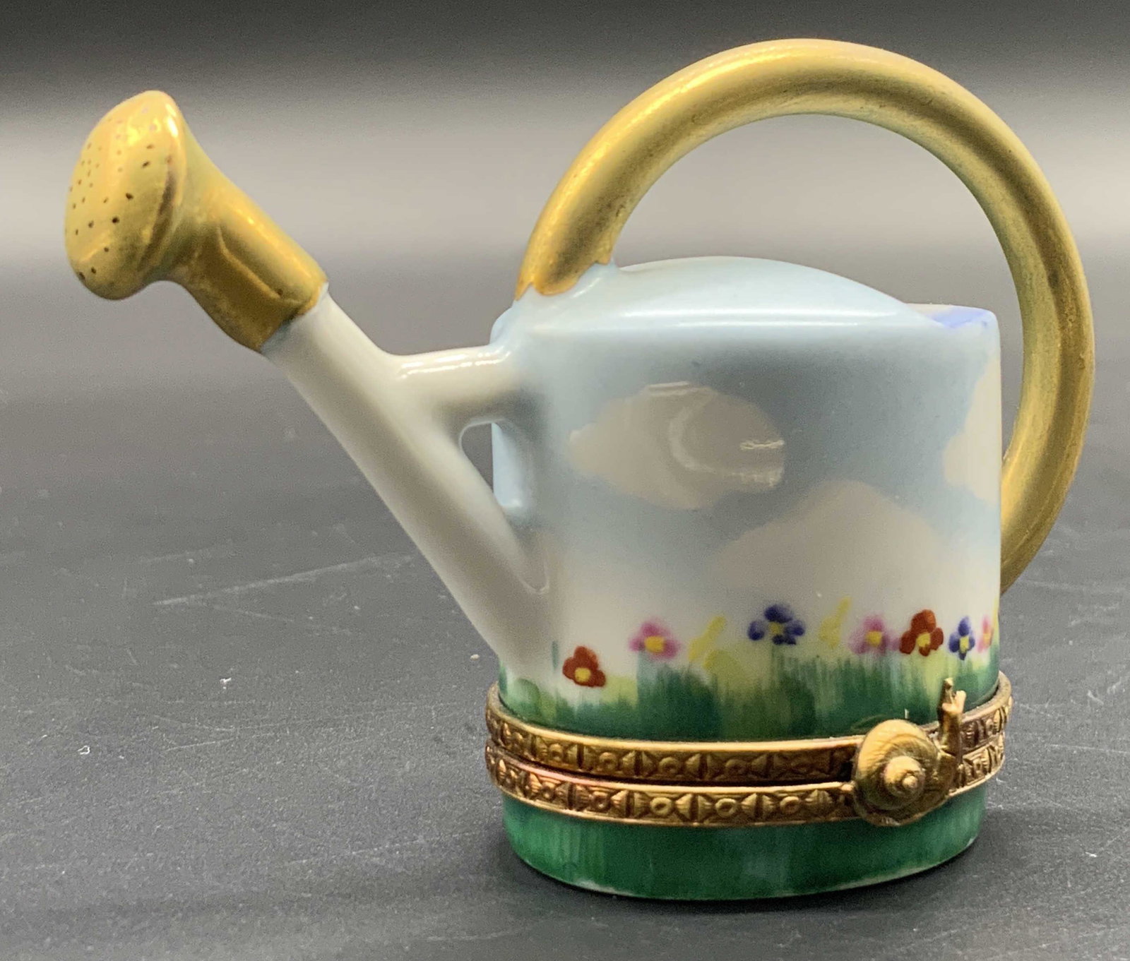 LIMOGES FRANCE ROCHARD Porc Watering Can Pill Box: A hand painted porcelain watering can figural pill box. Opens with metal hardware. Obverse of metal hardware features a snail motif. Hardware needs adjustment, does not stay closed. Underside signed L