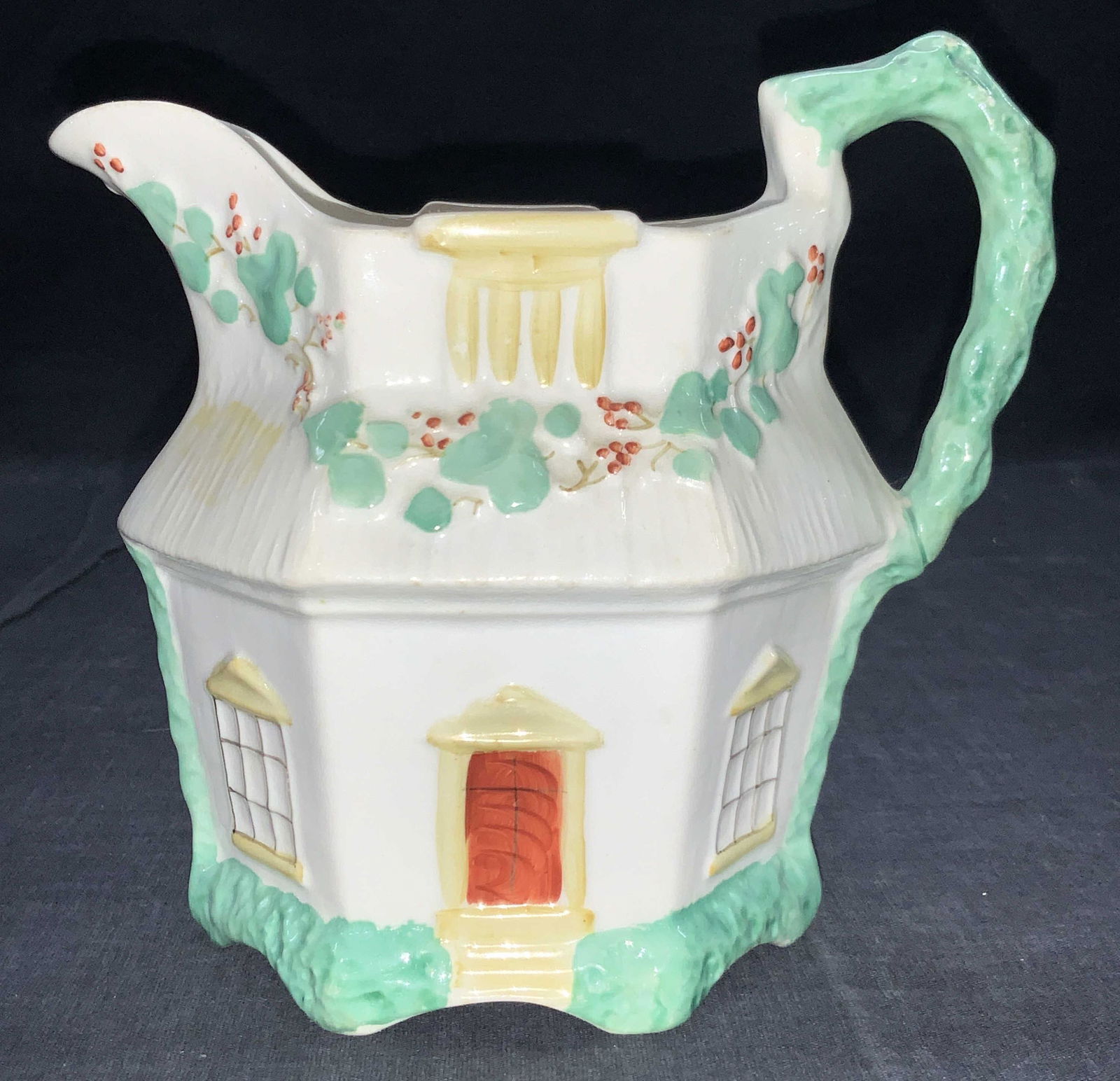 Hand Painted Staffordshire Porcelain Pitcher: Hand painted english house Pitcher with lipped rim and side handle. Base is white and teal toned handle and foliage, door is rust orange with yellow accents over door and windows. Approximately 5.75 i