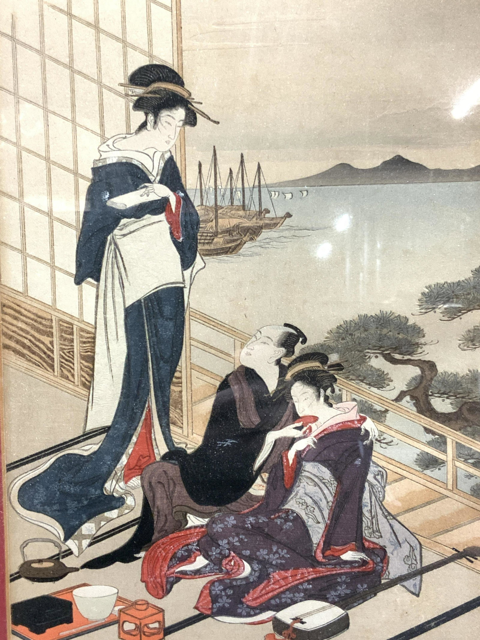 Utamaro Kitagawa Japanese Woodblock Art: Japanese woodblock art impression depicting a man sitting with a geisha, with guitar on floor with a food tray in front of them, the man looks up at another geisha in blue robes. Approximately 18 x 14