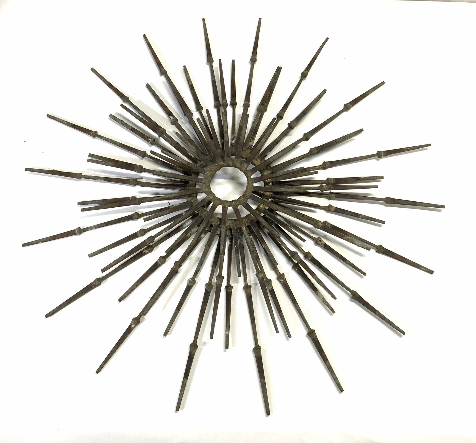 Brutalist Mid Century Metal Wall Sculpture: Sculpture is metal mid Century brutalist style. Sculpture has 3 rows of spokes. Sculpture Measures approx 26 inches wide. Sculpture, metal sculpture, wall sculpture, metal wall sculpture, brutalist mi