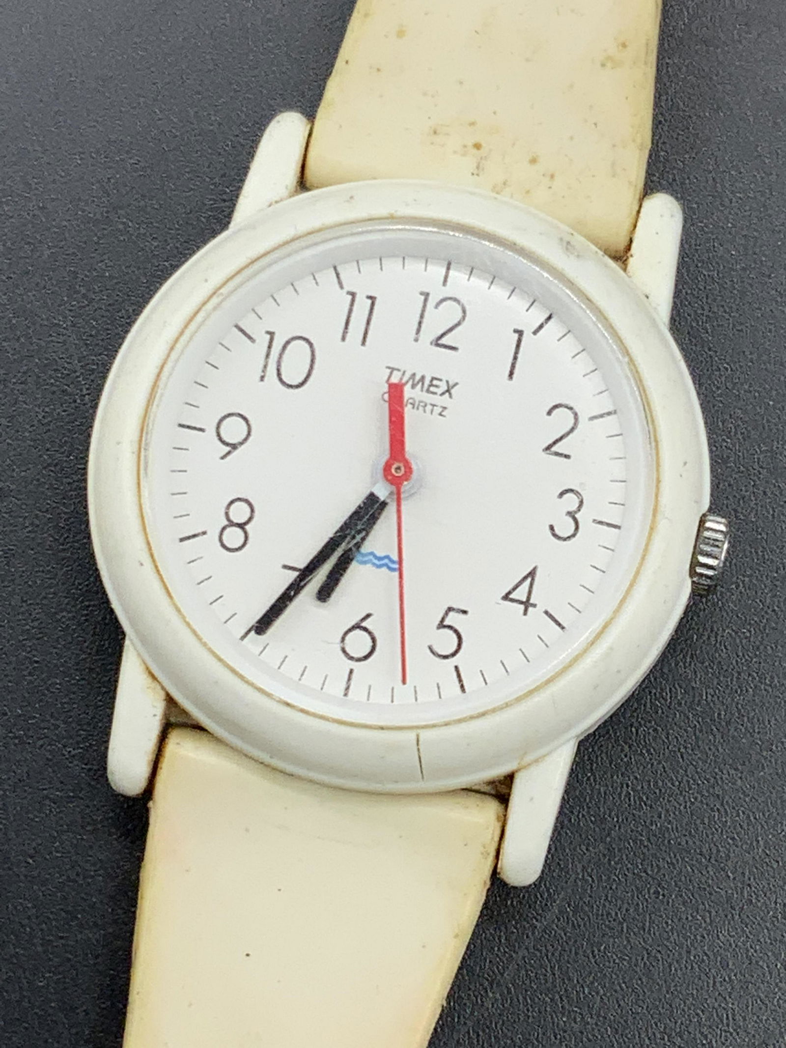 TIMEX Quartz Water Resistant Wristwatch: Cream hued composite material water resistant wristwatch. Watch face reads TIMEX QUARTZ. Reverse reads Water Resistant, Stainless Steel Back, TIMEX, HONG KONG. Measures approx 8 inches in length. Not
