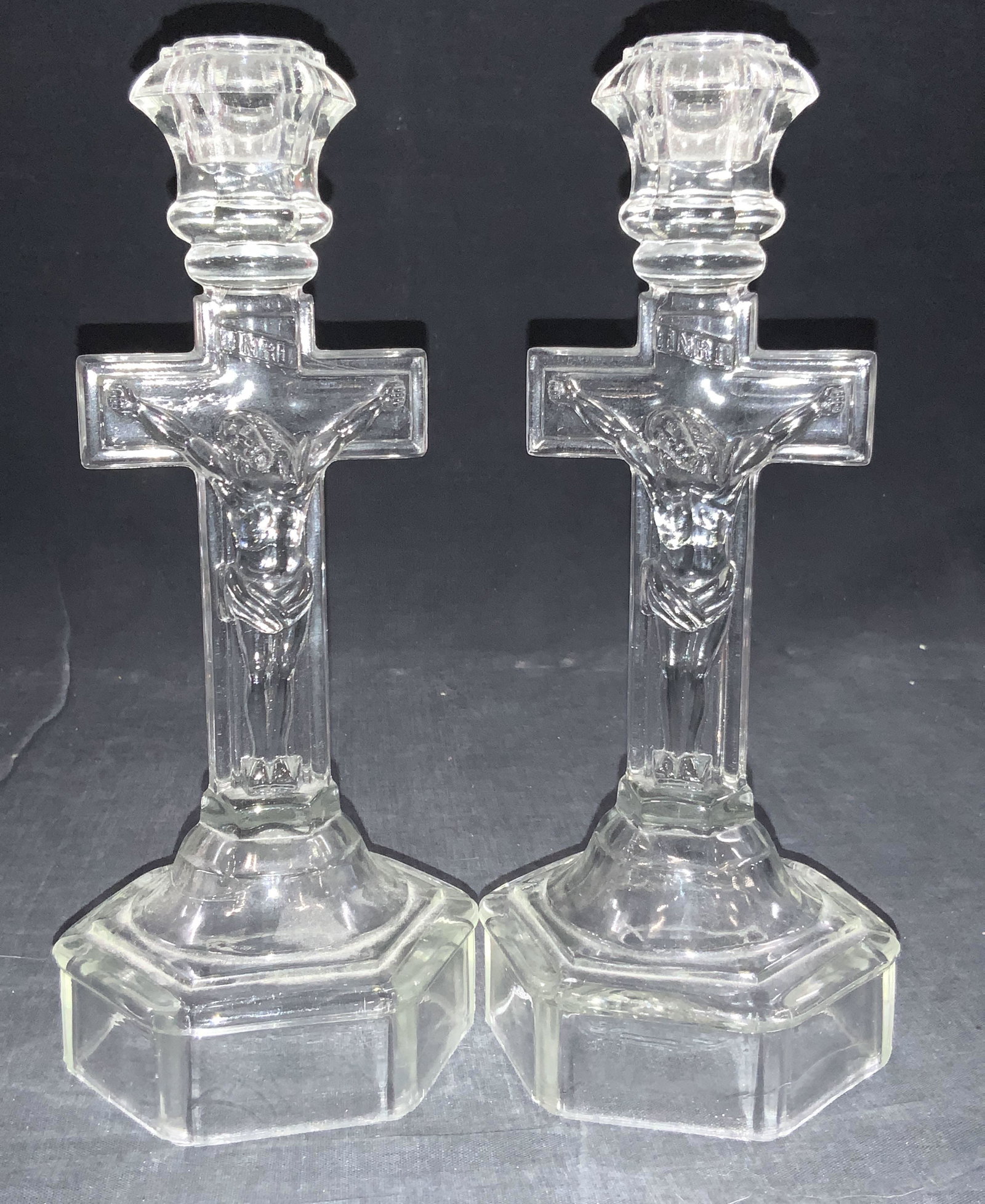 Pair Vintage Clear Molded Crucifix Candle Holders: Pair of clear molded glass candle holders depicting Jesus on the crucifix on the stem of the stem. Base is hollow with solid stem and rest of body. Approximately 10 inches tall. Vintage molded glass, 