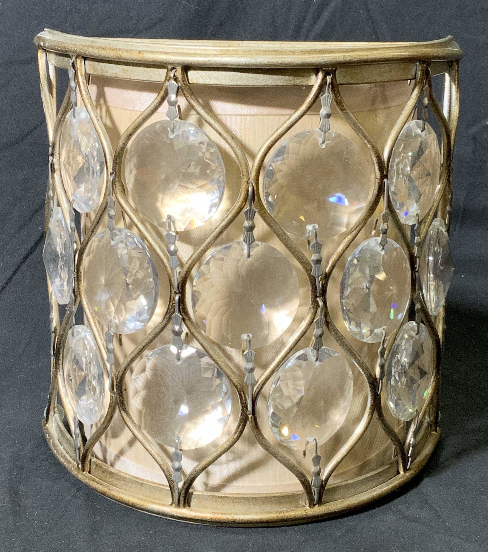 ASPIRE Gold Tone Bejeweled Wall Sconce: Aspire distressed finish gold tone wall sconce with prismatic colorless crystal decoration and beige shade. Metal, acrylic, and fabric. Marked Factory: Aspire on sticker to hardware. Measures approx. 