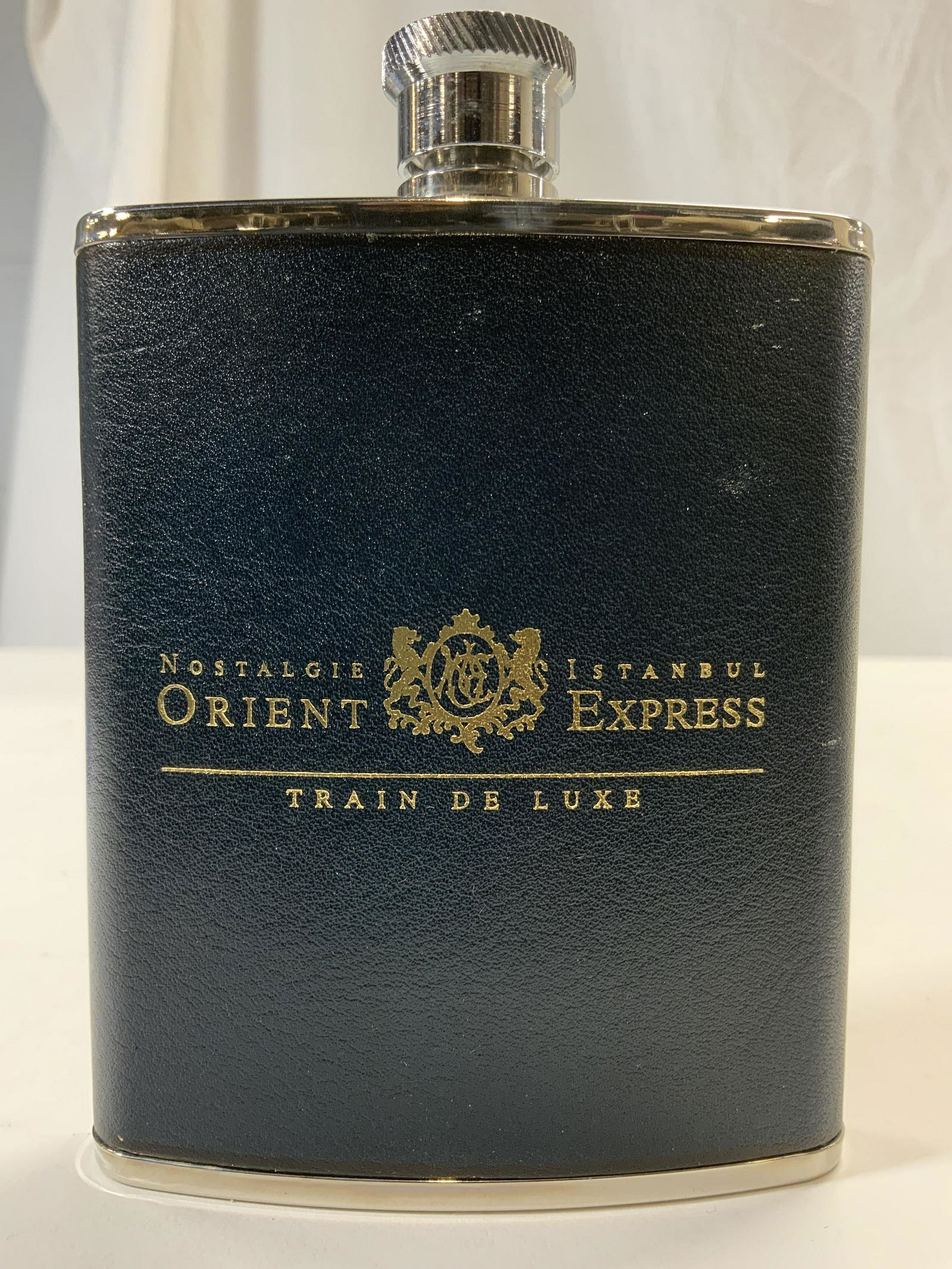 ORIENT EXPRESS Flask In Box GERMANY: Flask in inscribed NOSTALGIE ISTANBUL ORIENT EXPRESS TRAIN DE LUXE. Flask is lined in navy toned pebbled leather. Piece measures approx 5.5 inches tall 4 inches wide. Flask, liquor flask, orient expre