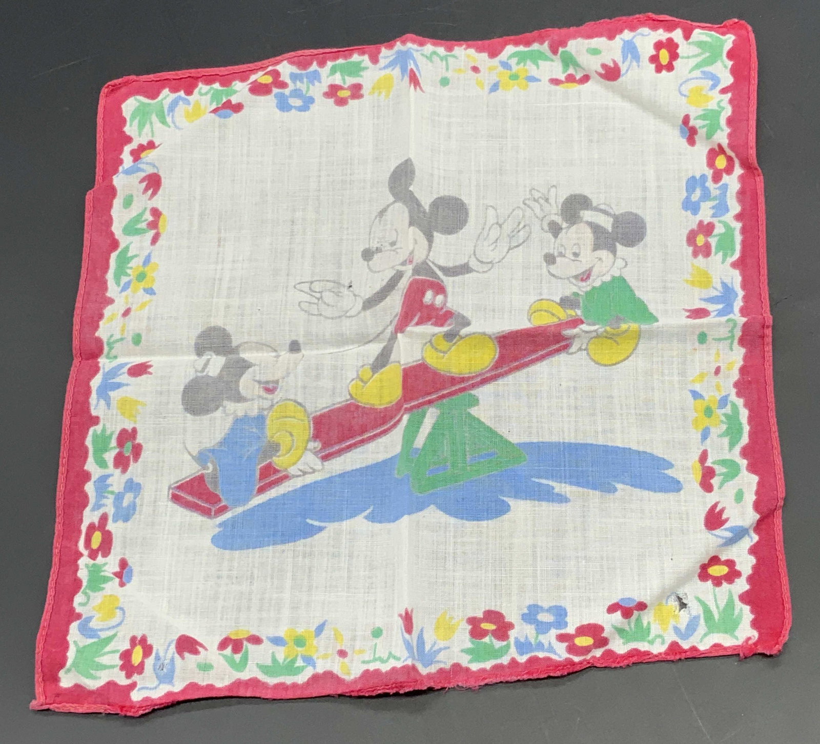 Vintage Mickey Mouse See-Saw Handkerchief: A vintage soft hand, rolled edge handkerchief / Hankie featuring the image of a Mickey Mouse & two other Disney Mice playing on a see-saw. Floral border. Soft hand, possibly silk or cotton or blend. N