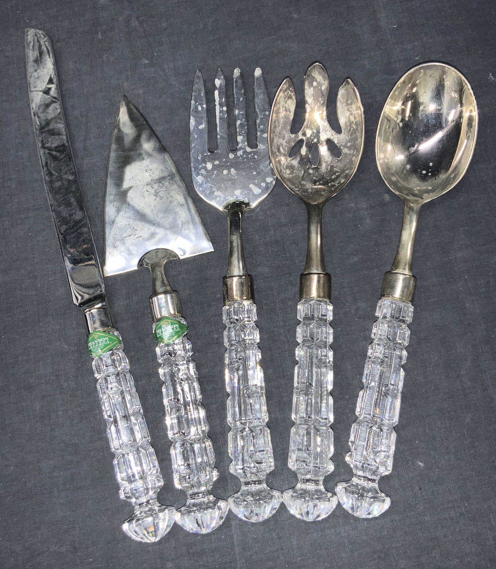 Shannon Crystal Handled Serving Utensils: Set of 5 crystal handled serving utensils. 1 carving knife with serrated edge, 1 take knife, fork, spork and spoon, all with cut crystal handles, marked on handles, Shannon Crystal, 24% Lead crystal.