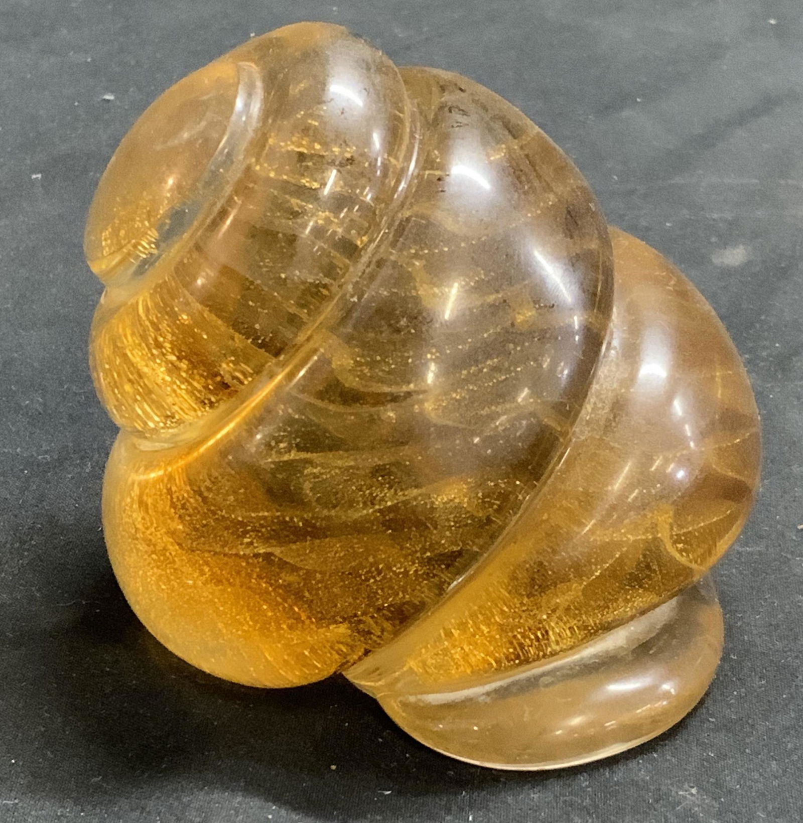 Gold Art Glass Shell Paperweight: Art glass shell paperweight with swirled gold tone interior. Measures approx. 3 inches diameter. Piece has weight. Some surface wear consistent with exposure. Shell, art glass shell, art glass, studio
