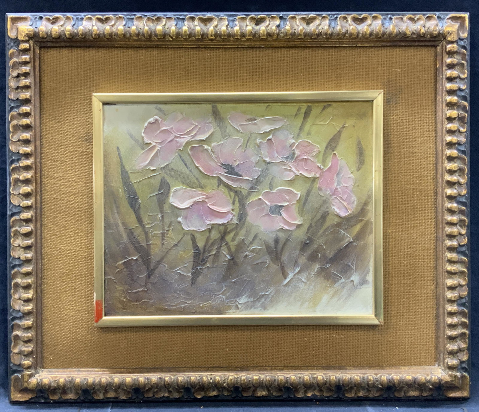 Double Framed Floral Oil Painting: Oil painting depicting pink flowers amongst a green background in muted colors. Double framed with exterior frame having carved wooden edges with gold patina, secondary frame around painting is gold m