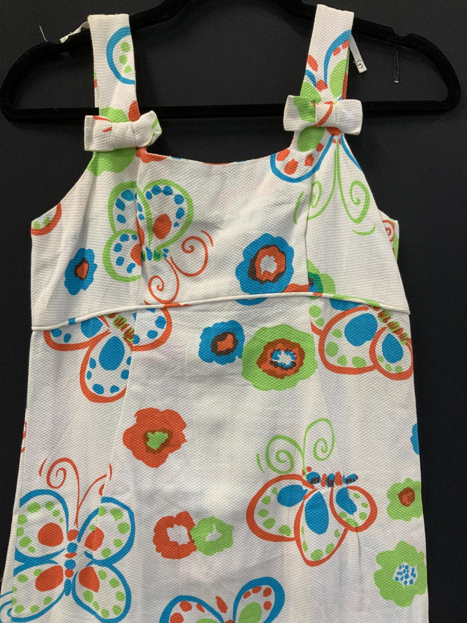 Toby Tanner Textured Cotton Butterfly 60s Dress: long sleeveless dress with bright colored butterflies on white background. Colors of lime, royal blue, and orange butterflies. Empire waist, bows on straps. Signed label sewn to garment reads Toby Tan