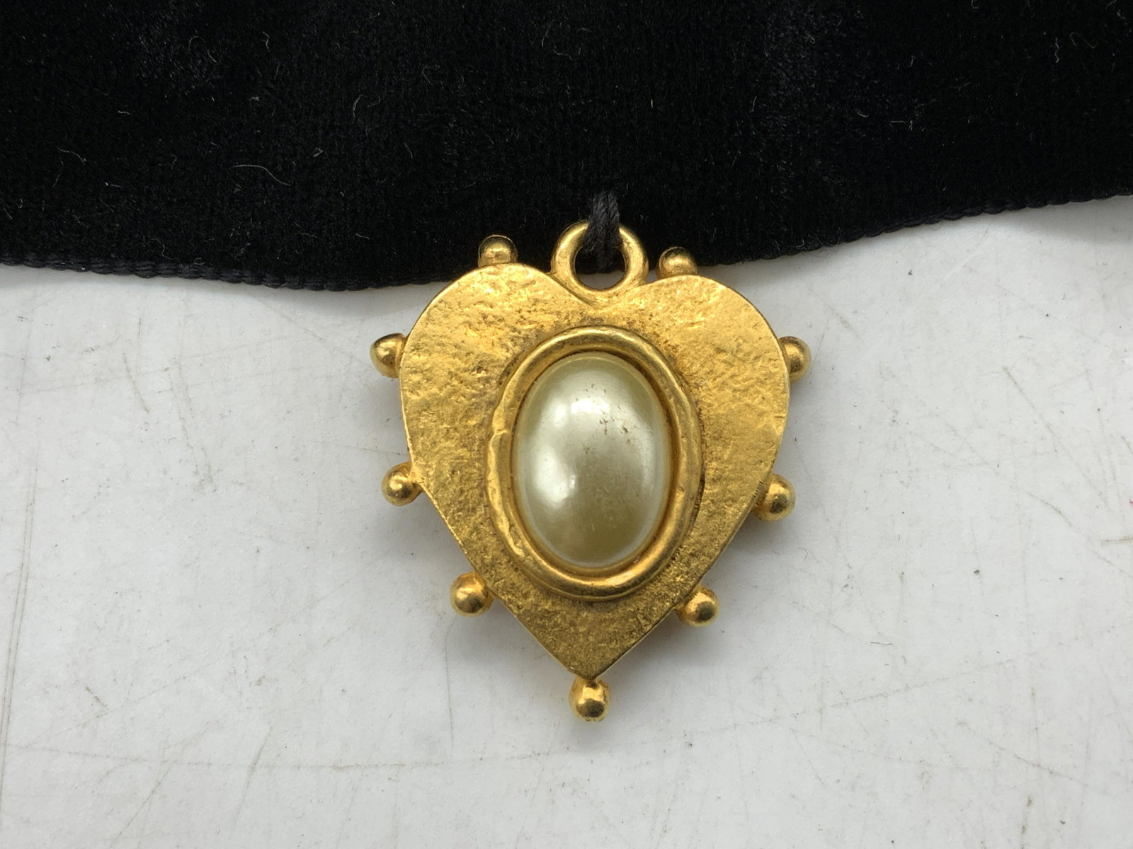 Velvet Choker w Heart Pendant & Faux Pearl: Black velvet choker necklace with Velcro closure, gold tone heart pendant, and faux Pearl Cabochon. Some surface wear consistent with exposure. Measures approx. 15.25 inches long. Choker, velvet choke