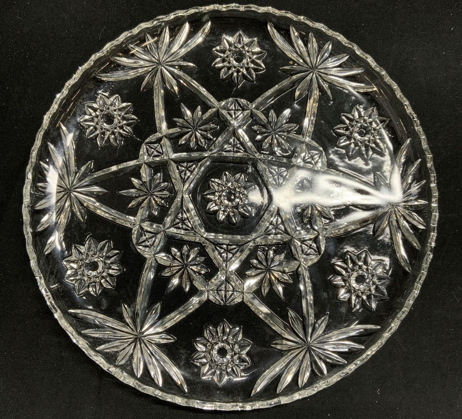 Round Cut Glass Serving Platter: Round cut glass serving platter with starburst design. Measures approx. 13.5 inches diameter. Some surface wear consistent with exposure. Serving platter, platter, serving dish, Serveware, tableware,