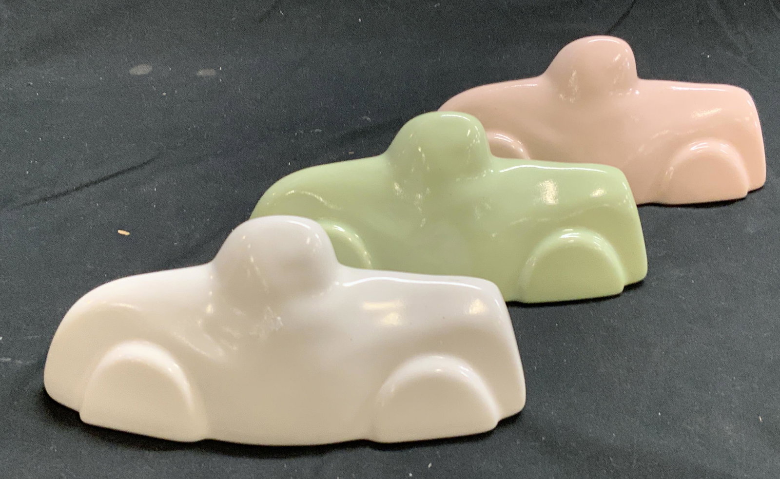 Set 3 BILAR Malin Ceramic Limousine Figurines: Set of 3 white, green, and pink ceramic limousine figurines. Signed on sticker to underside AHLGRENS BILAR by MALIN STOCKE WIKSTROM and signed MALIN to body. Measure approx. 5.75 x 2 x 2.5 inches. All