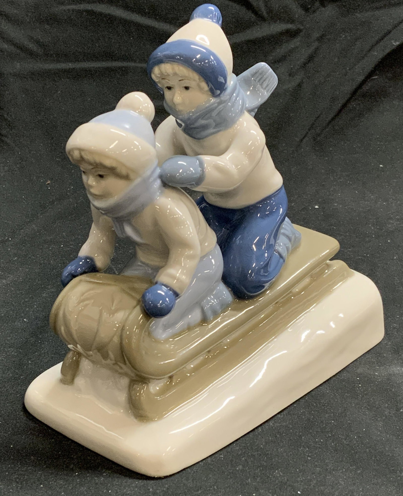 PORCELAIN DE CUERNEVACA Sledding Figurine: 1992 Porcelain de CUERNEVACA figurine. Feature two children sledding. Trademarked to underside, measures approx. 6 x 3.25 x 6.25 inches. In good condition. Porcelain de CUERNEVACA, porcelain de CUERNE