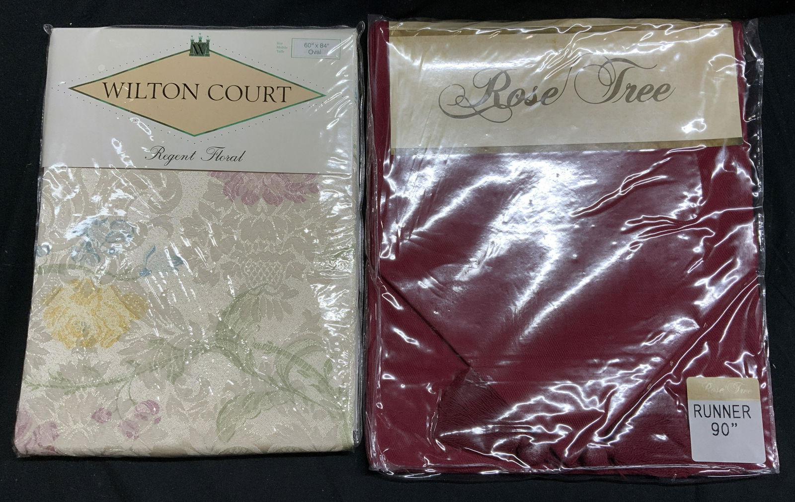 Lot 2 WILTON COURT & ROSE TREE Table Linens NIP: Wilton Court Regent Floral pattern oval table cloth. Measures 60 x 84 inches. Cotton and polyester blend. New in package. Rose Tree burgundy table runner. Measures 90 inches long. 100% cotton. New in