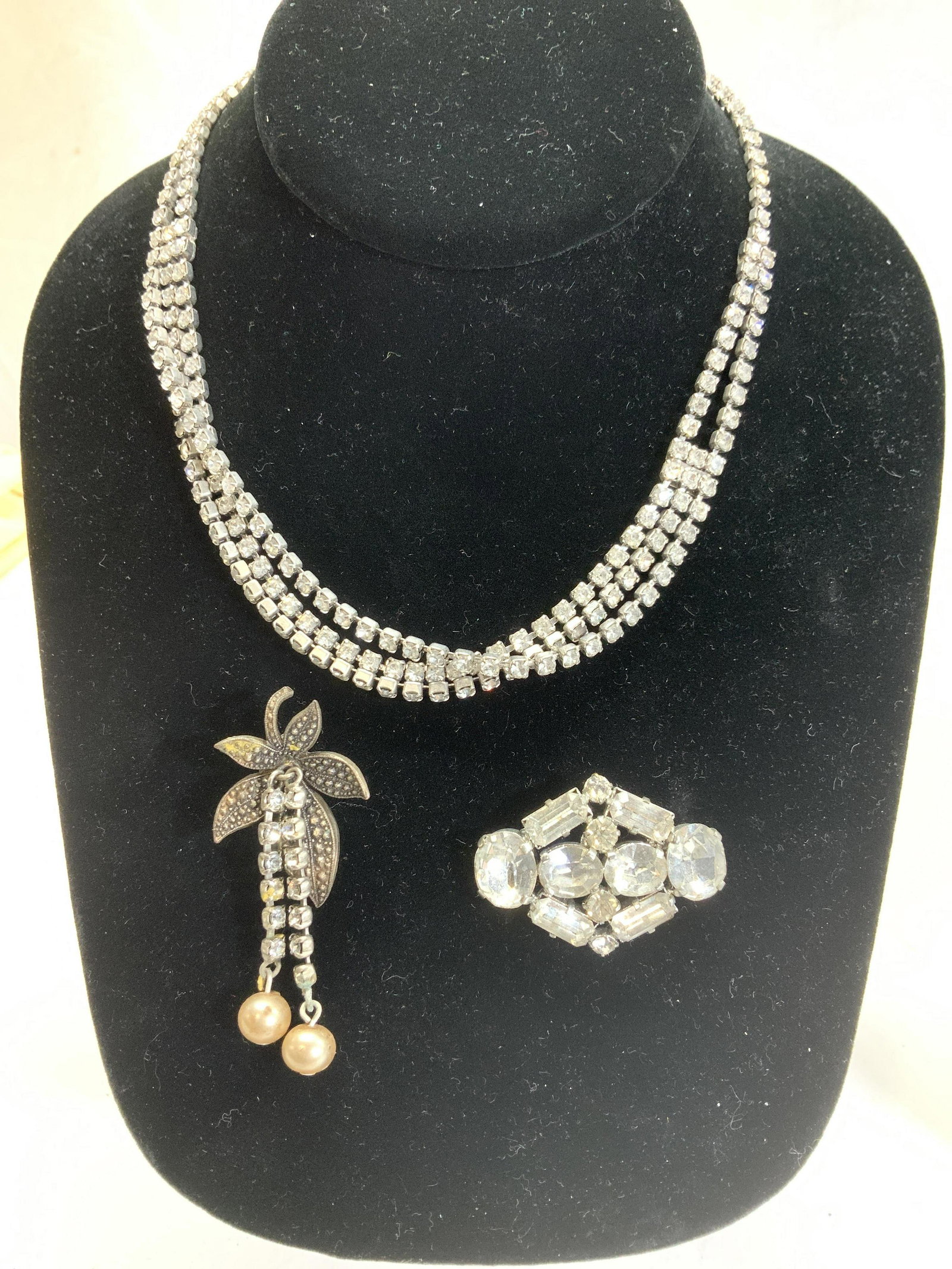 Lot 3 Rhinestone Brooches & Choker Necklace: Vintage rhinestone jewelry, 15.5 in necklace with hook clasp. Triangular Clear rhinestone brooch, 1.5 x 1.25. Leaf brooch with dangling rhinestone tassels , 2 in long. wear to piece on this brooch . F
