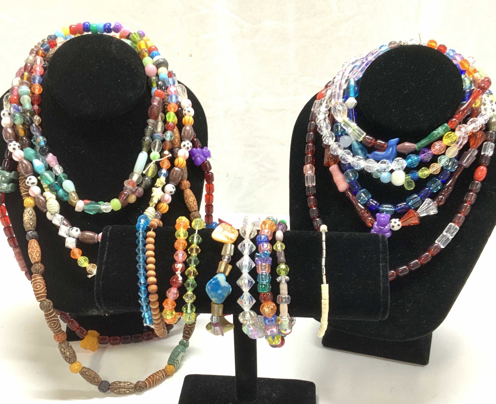 Lot 21 Whimsical Beaded Necklaces & Bracelets: Necklaces and bracelets, all stretch , longest necklace is the multi colored wood style , 26 in. Long. Many beads are colorful plastic with an iridescent coating. Some are glass. Other beads include s
