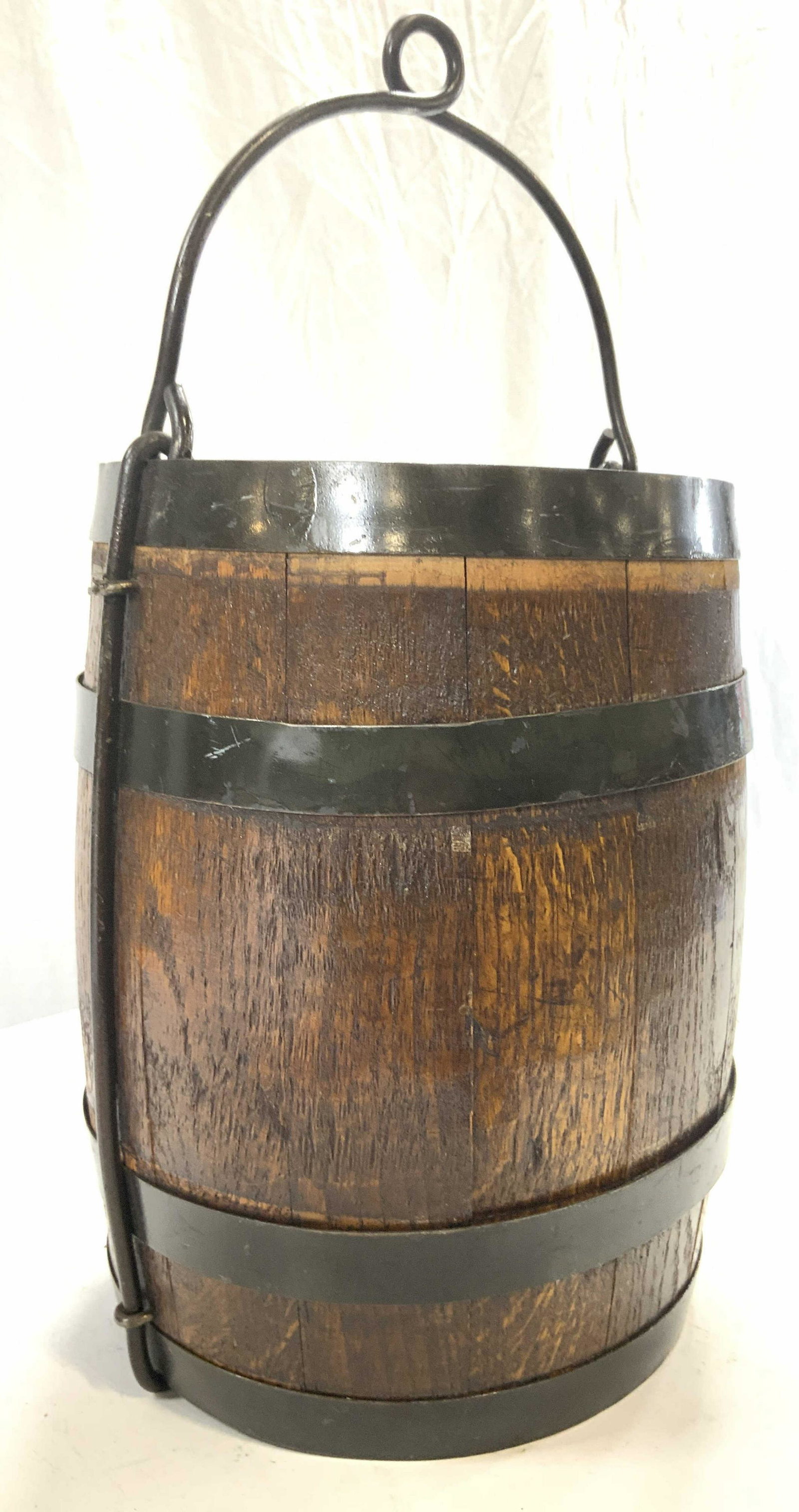 Vntg Metal Bound Wooden Barrel Basket W Handle: Barrel basket is vintage. Piece is brown toned & wooden with metal bounds. Piece has metal handle. Measures approx 18.5 inches tall with handle 10 inches wide. Barrel, barrel basket, metal bound barre