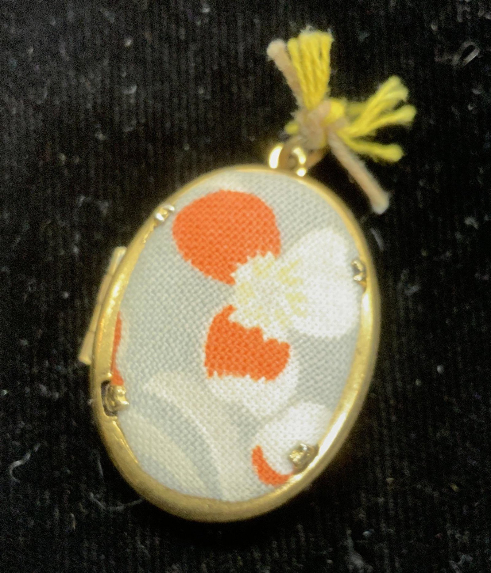 Fabric Covered Goldtone Locket: Grey and orange fabric covered oval locket with gold tone , opens to reveal 2 places for a picture. Measures 1.25 in long with bale, 7/8 in wide, and 3/8 in deep. vintage jewelry, Estate Jewelry, Cost