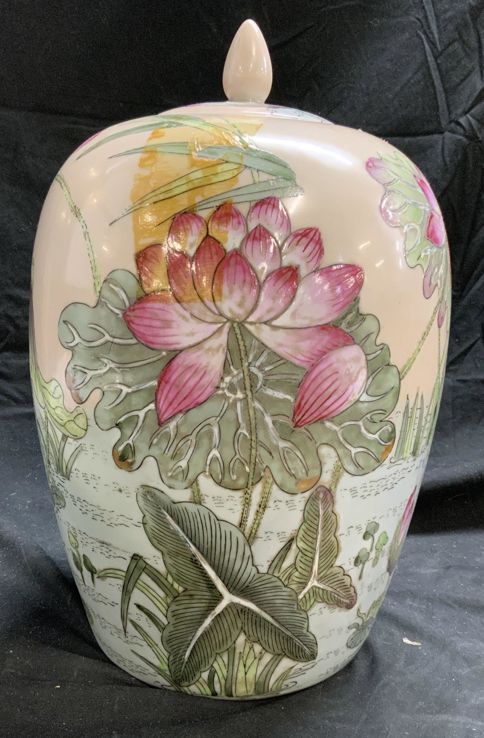 Asian Porcelain Lotus Ginger Jar Centerpiece: Asian hand painted porcelain ginger jar with lotus and crane motif in hues of green and pink. Measures approx. 9 inches diameter and 14 inches tall. Some surface wear consistent with exposure, tape re