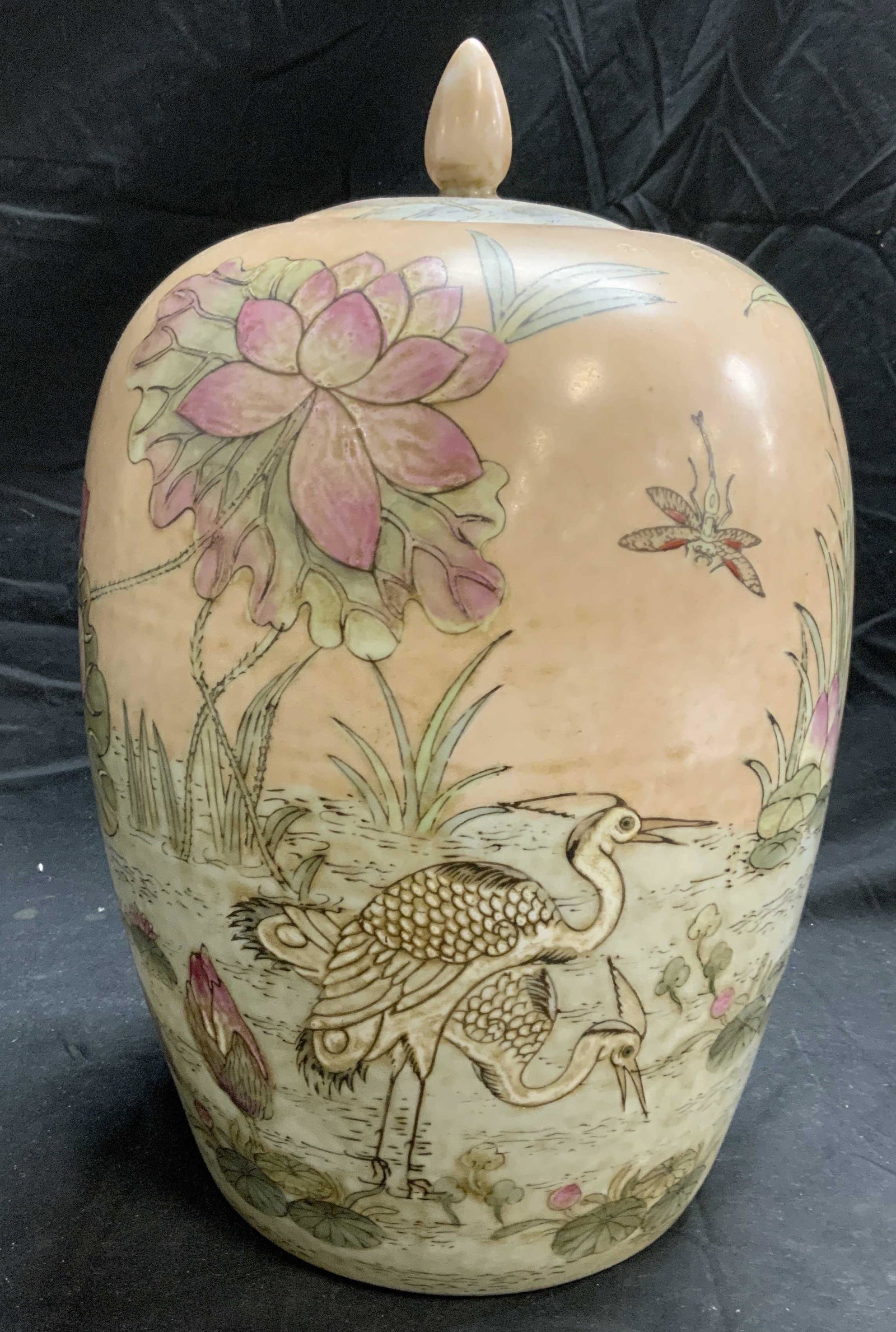 Asian Porcelain Lotus Ginger Jar Centerpiece: Asian hand painted porcelain ginger jar with lotus and crane motif in hues of green and pink. Measures approx. 9 inches diameter and 14 inches tall. Some surface wear consistent with exposure, tape re