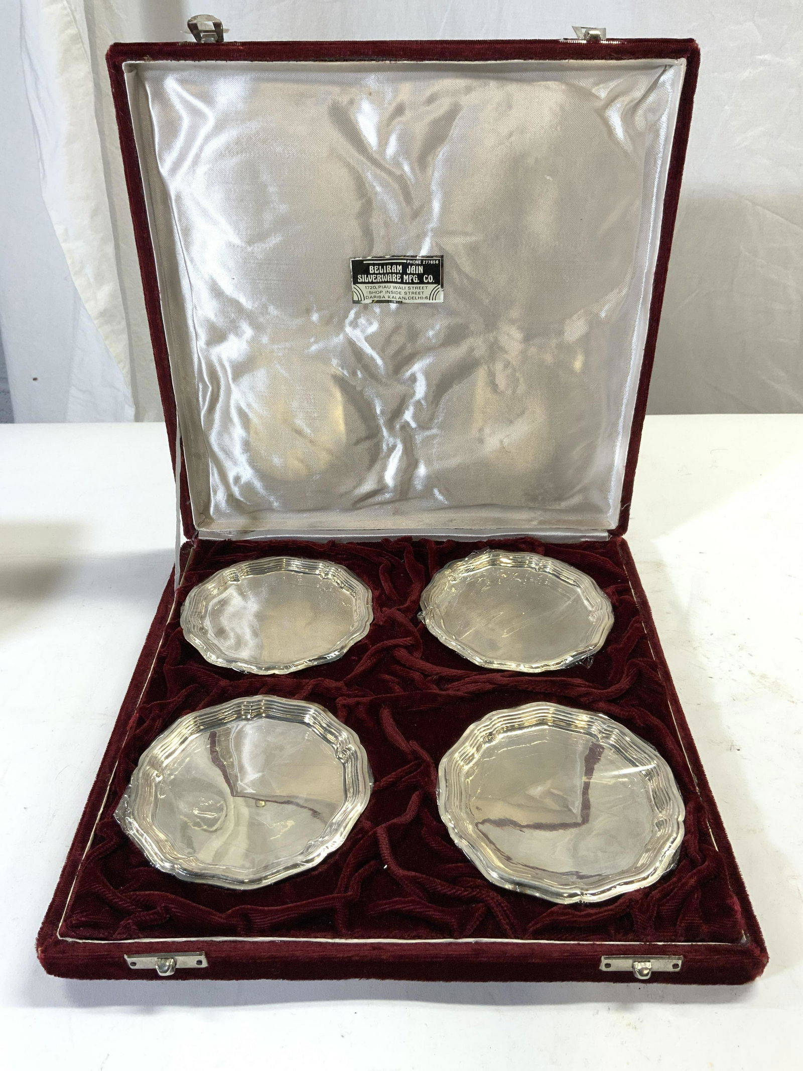 STERLING BELIRAM JAIN SILVERWARE MFG CO Salvers Bx: Tag inside box reads STERLING BELIRAM JAIN SILVERWARE MFG CO. Each salver is inscribed SILVER. Each salver measures approx 4.5 inches wide. Lot includes 4 salvers & box. Box is wine red toned & measur